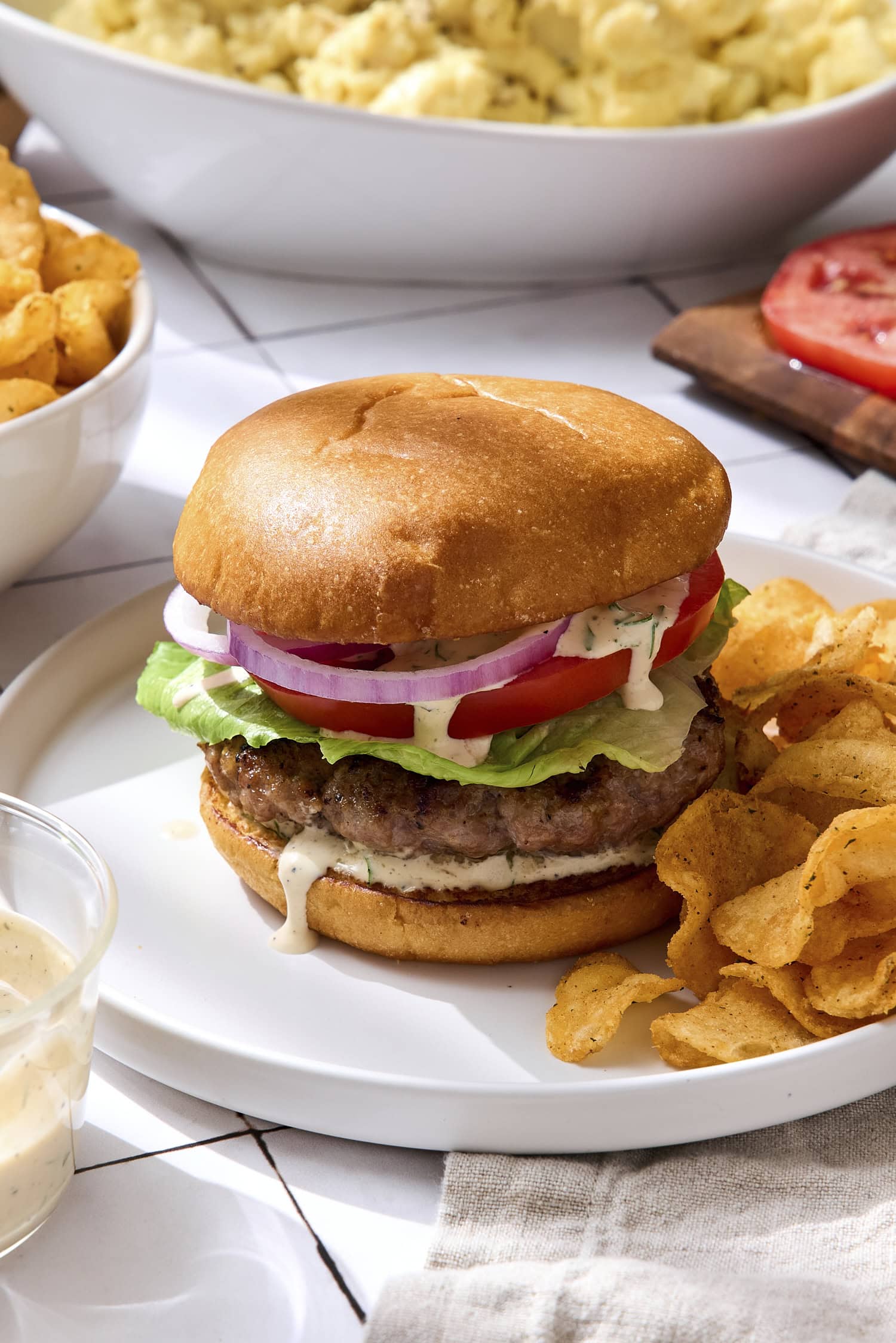 Grilled pork burgers with tomato, lettuce, onion, and homemade sauce.
