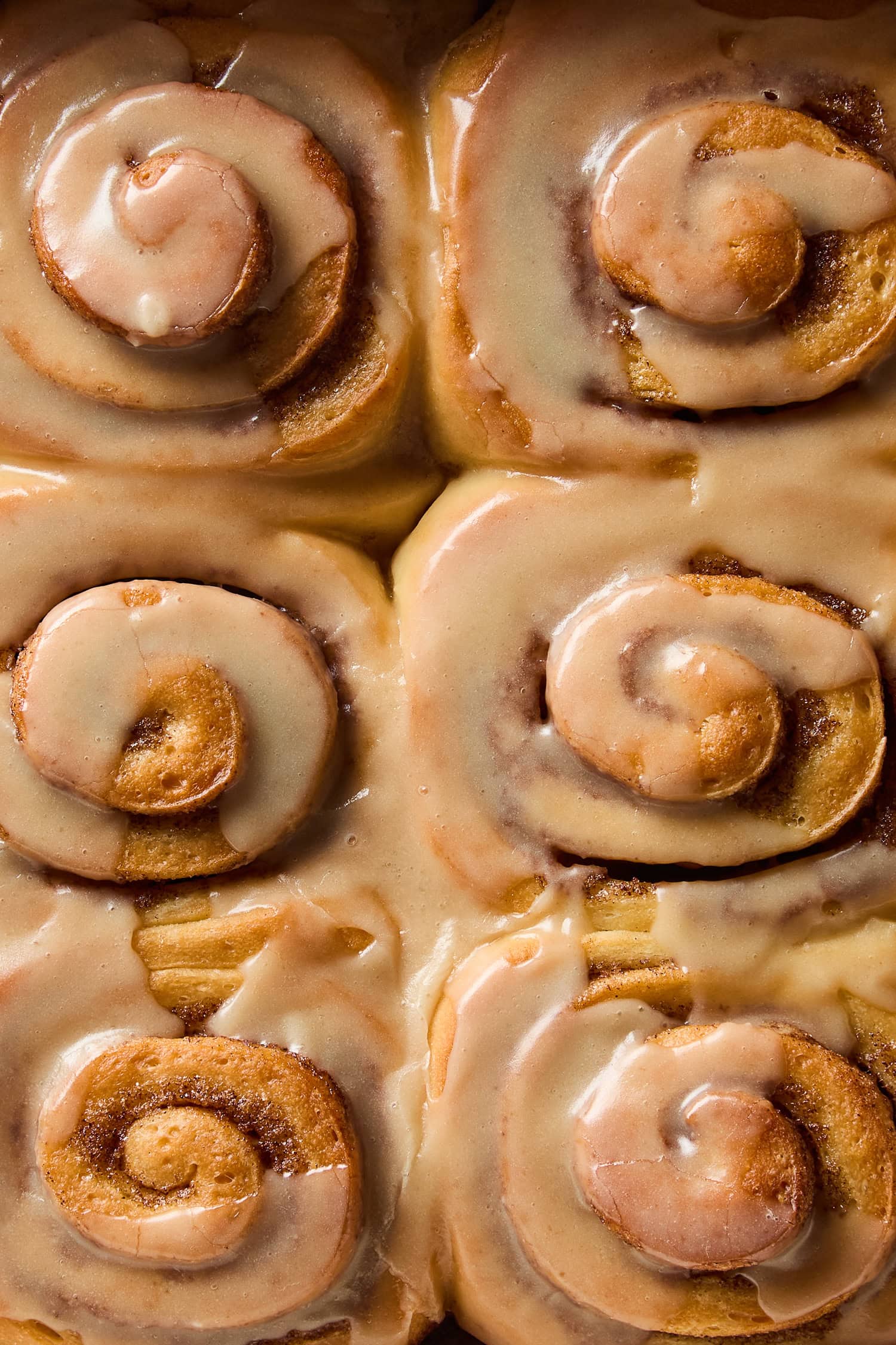 Brown butter frosting covering cinnamon rolls.