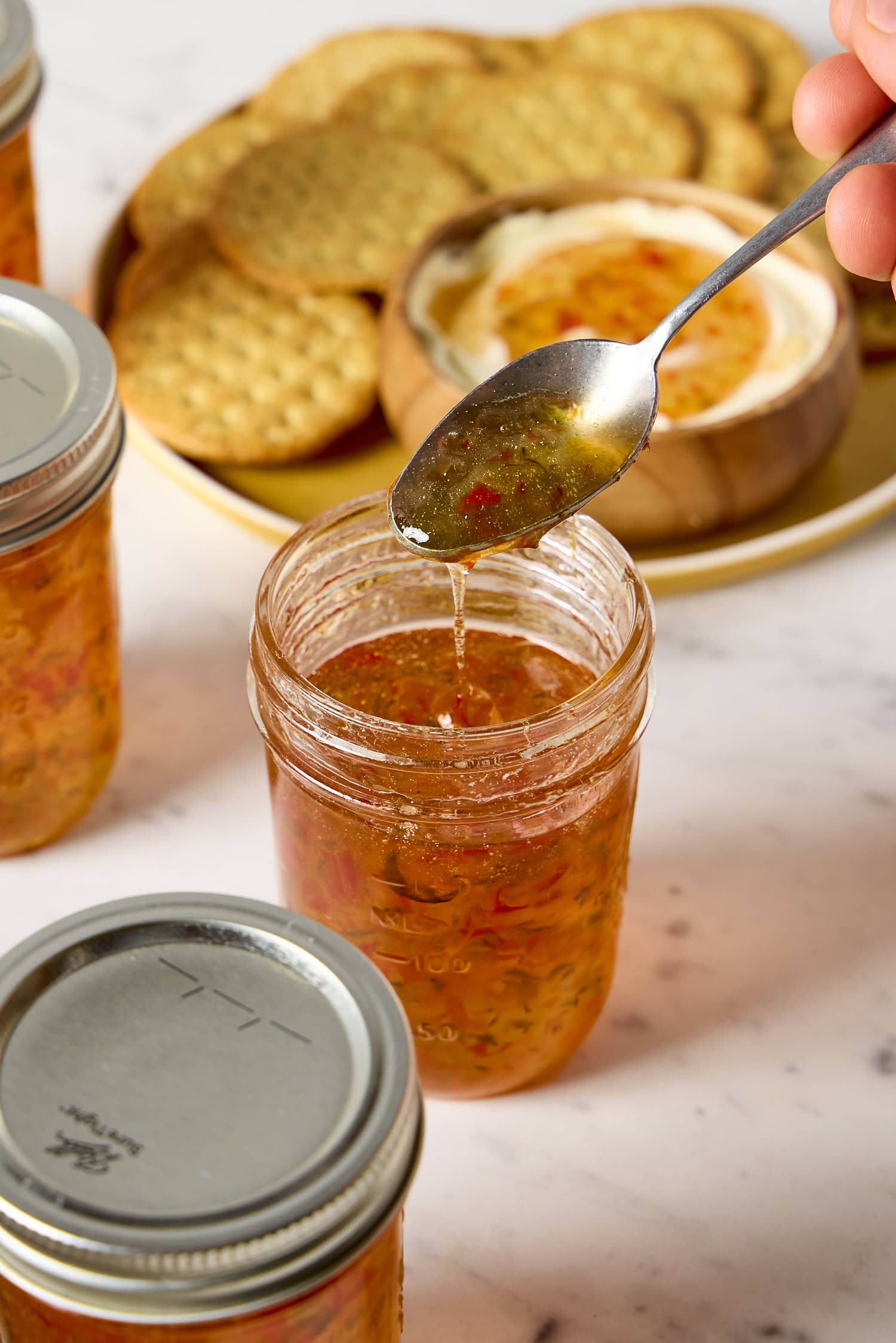 Spoon drizzling hot pepper jelly from jar.