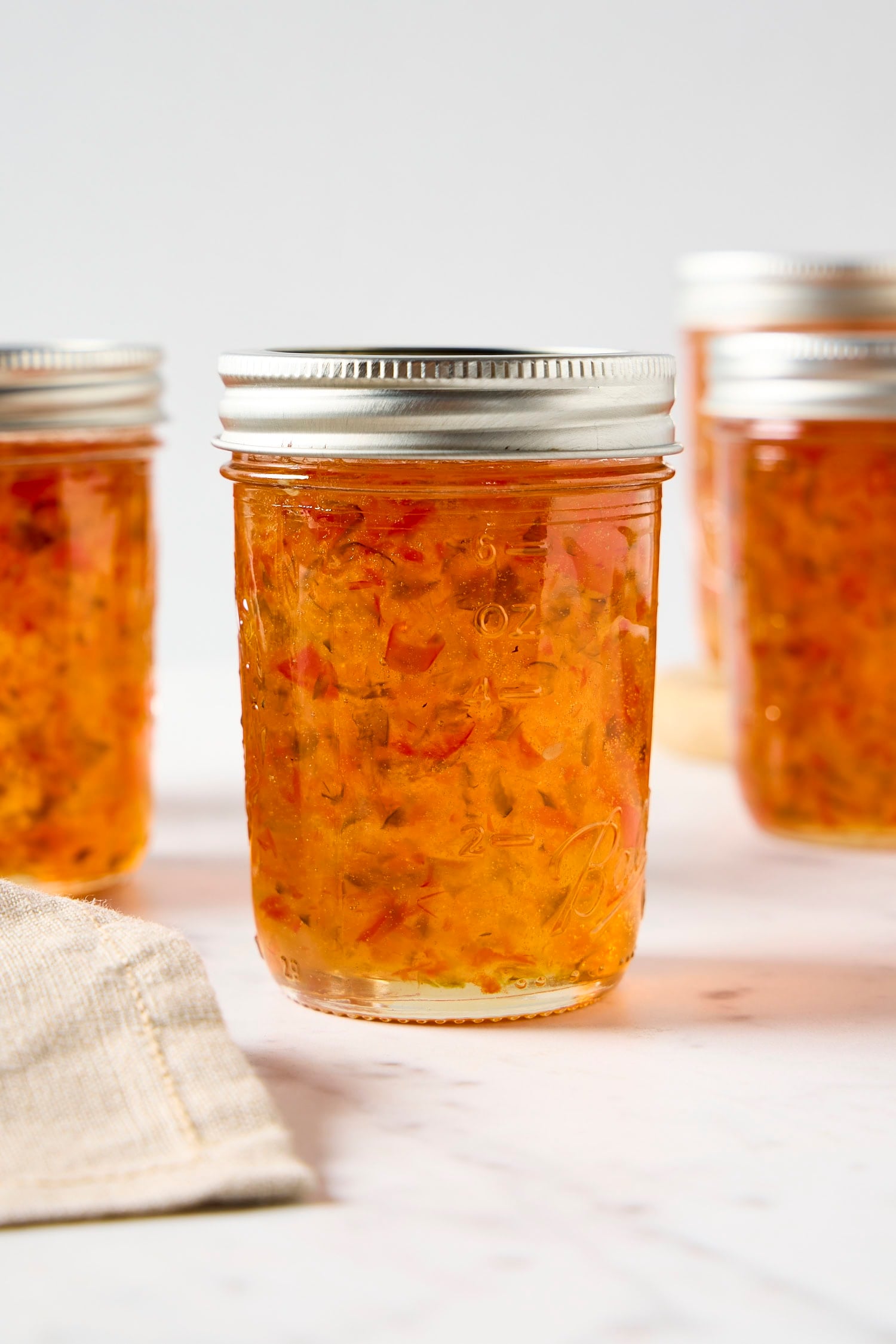 Jam jars filled with orange-colored hot pepper jelly recipe.