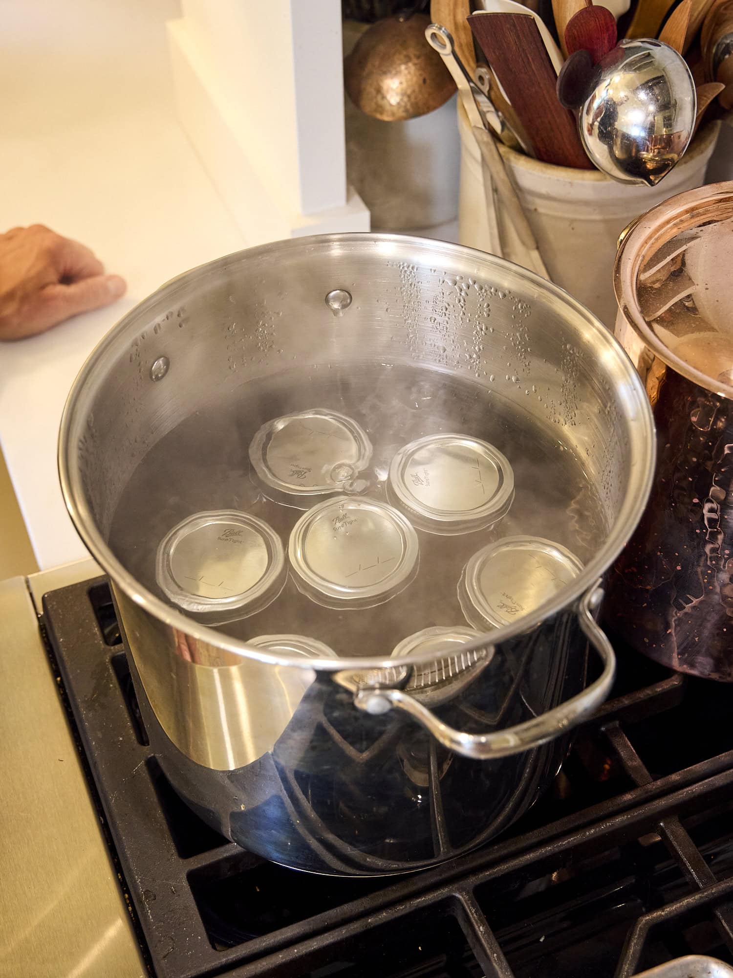 Jam jars filled with hot pepper jelly in water bath canner.