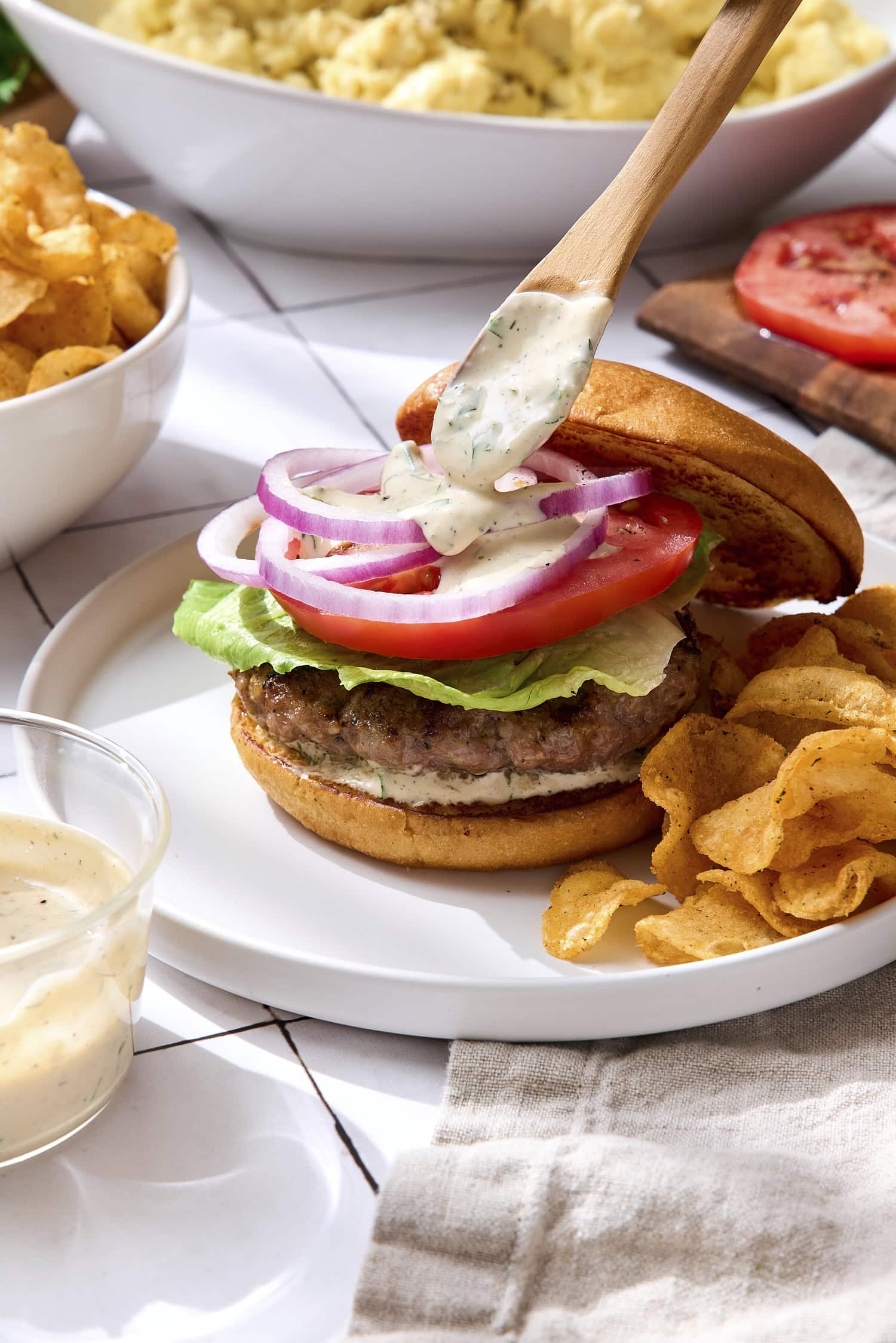 Sauce being poured on top of pork burger on a plate.