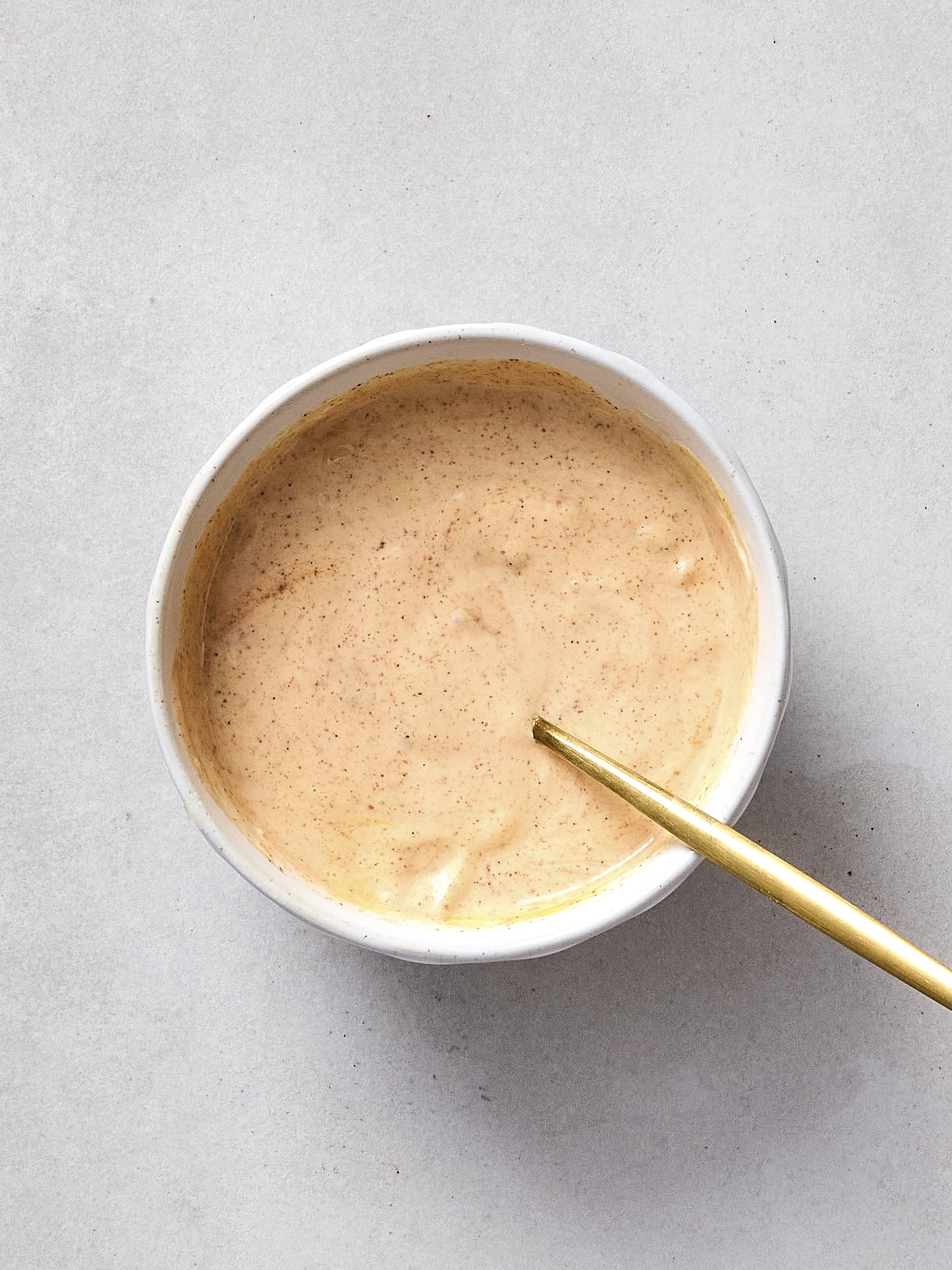 Mixing together burger sauce in white bowl.
