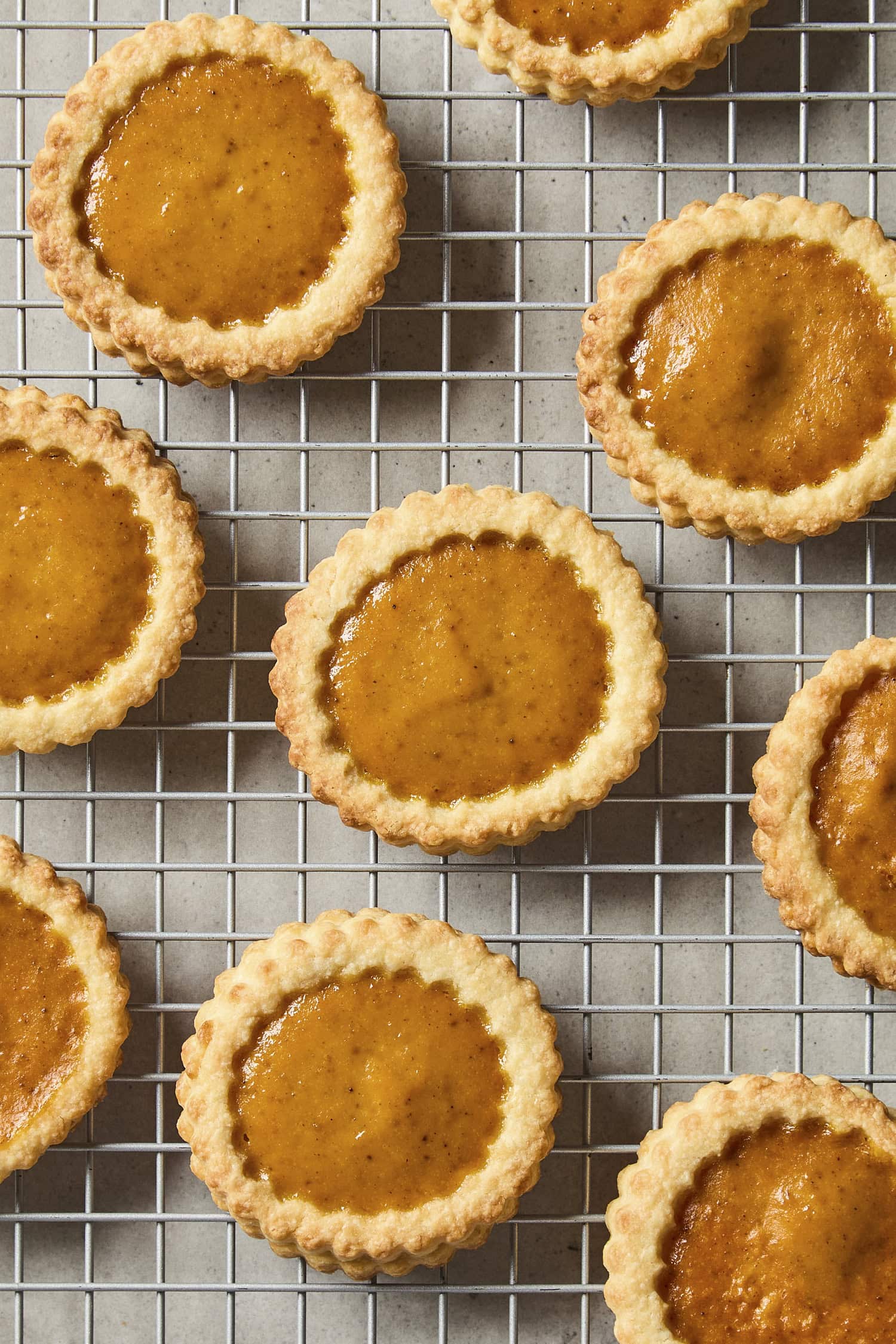 Baked small pumpkin pie cookies on cooling rack.