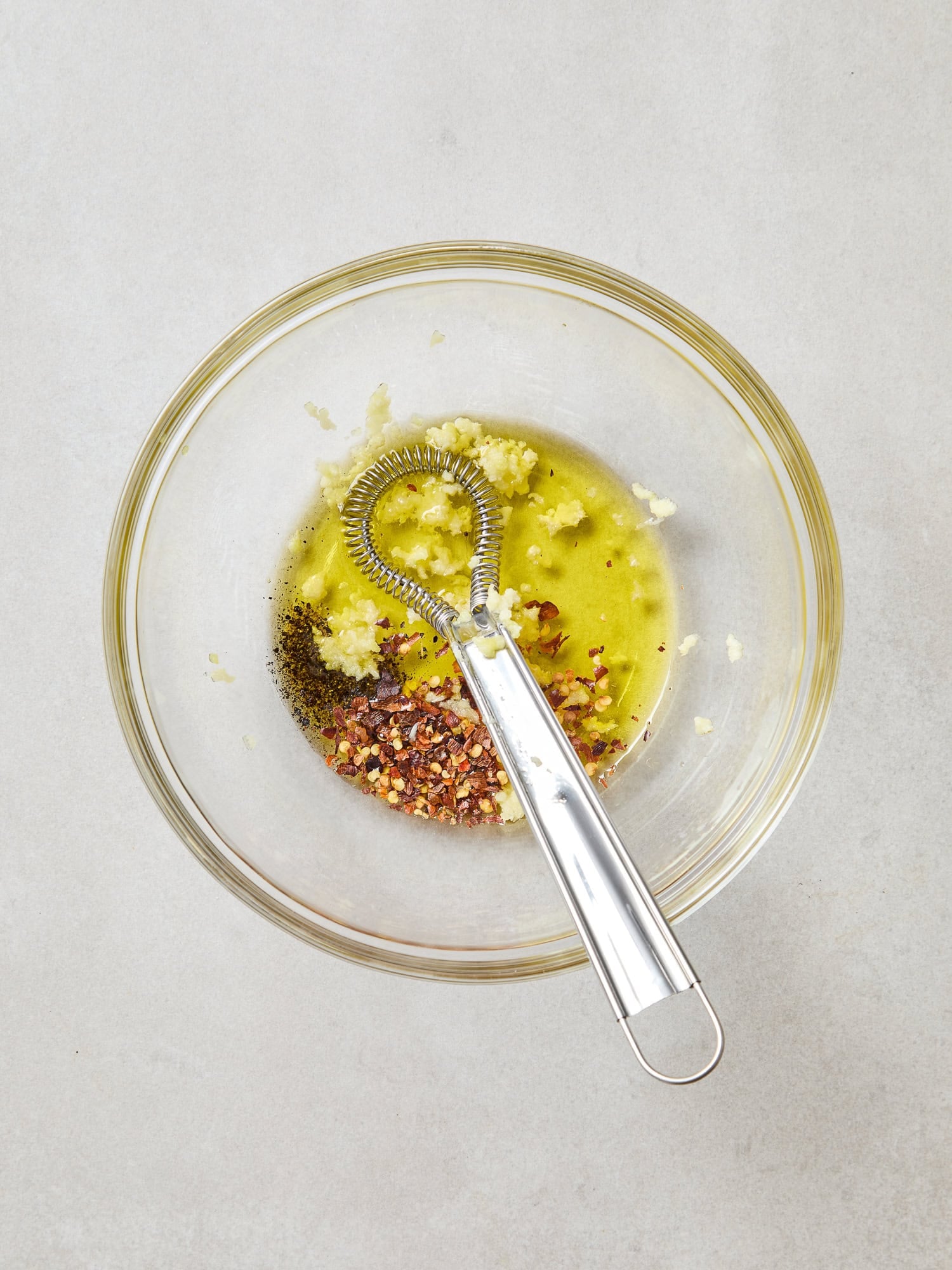 Ingredients for a spicy garlic vinaigrette in a bowl.