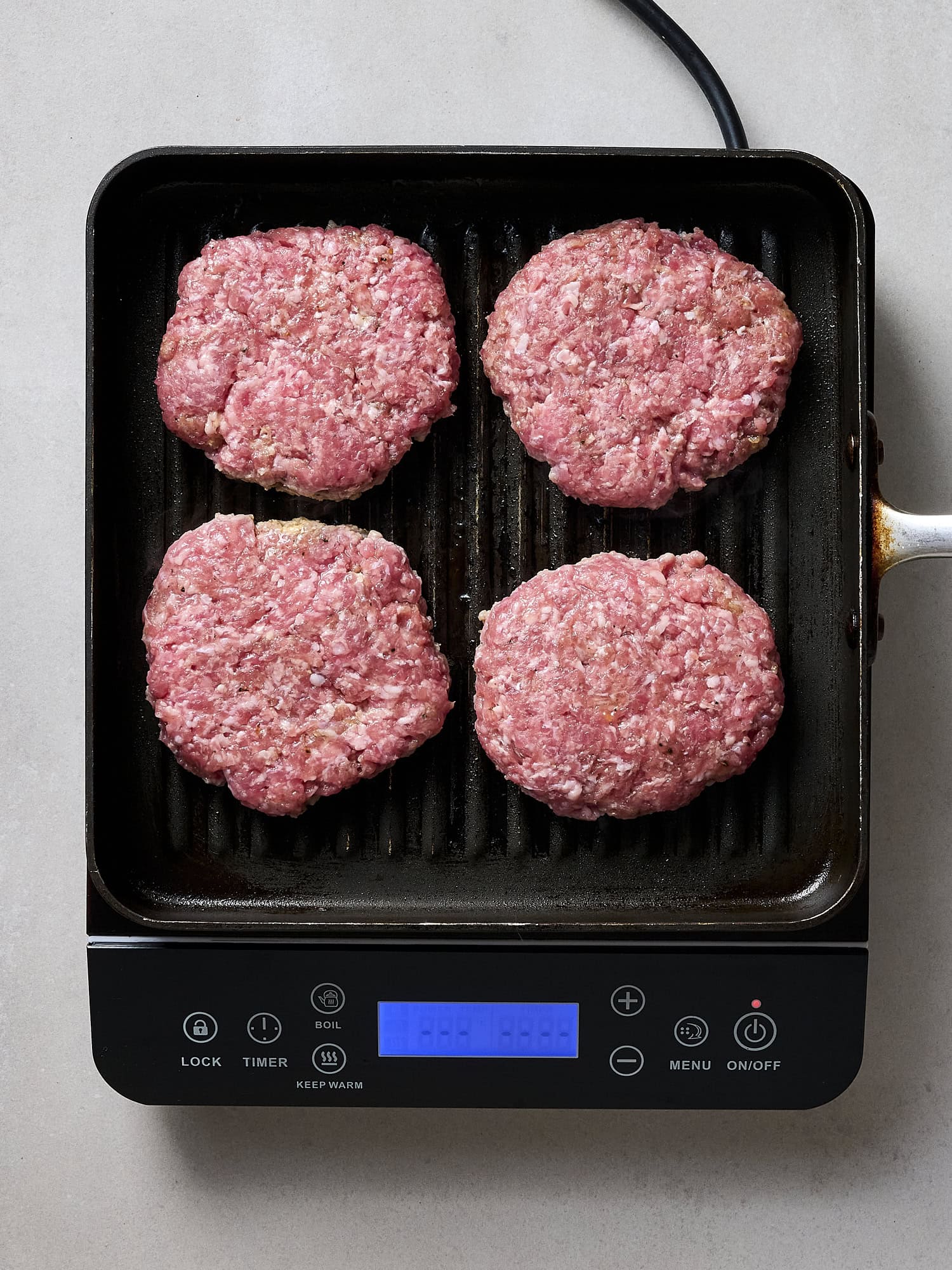 Uncooked pork burgers on grill pan.