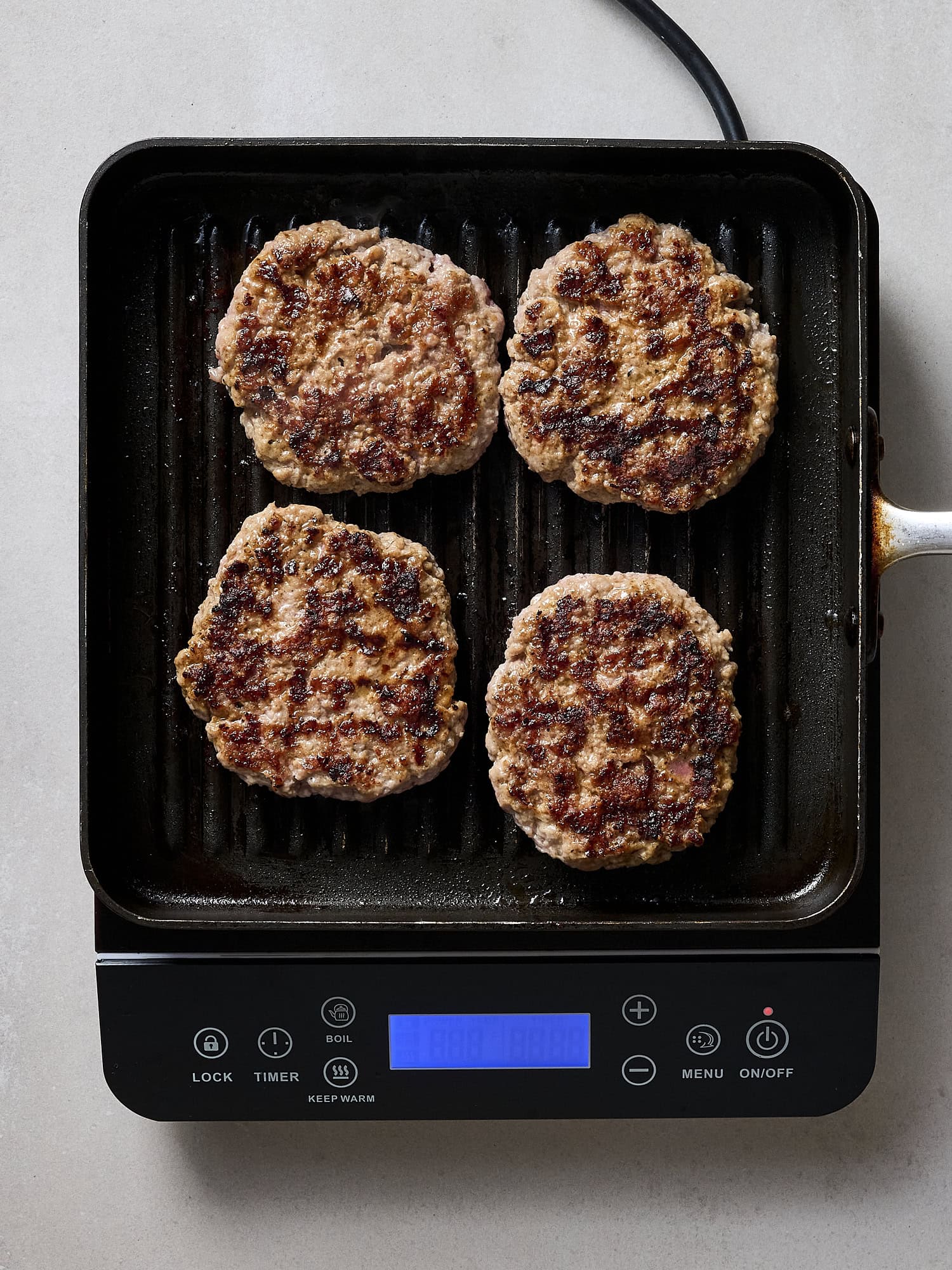 Grilled pork burgers sitting on grill pan.