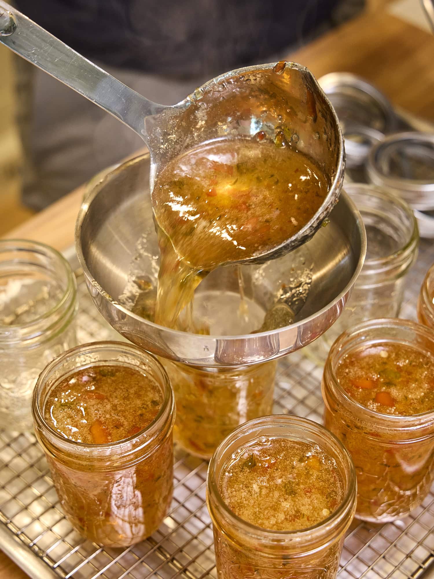 Pouring liquid hot pepper jelly in jam jars.