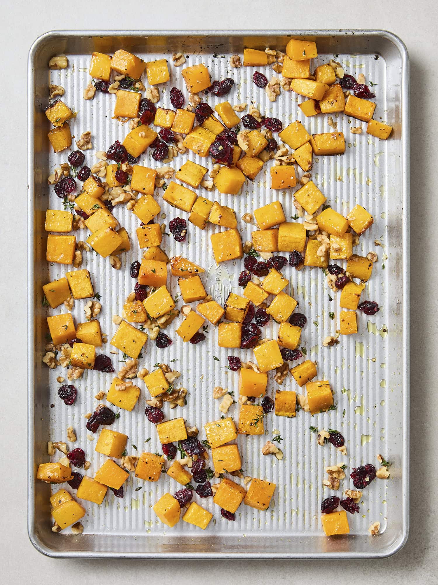 Roasted butternut squash on sheet pan with cranberries and thyme.