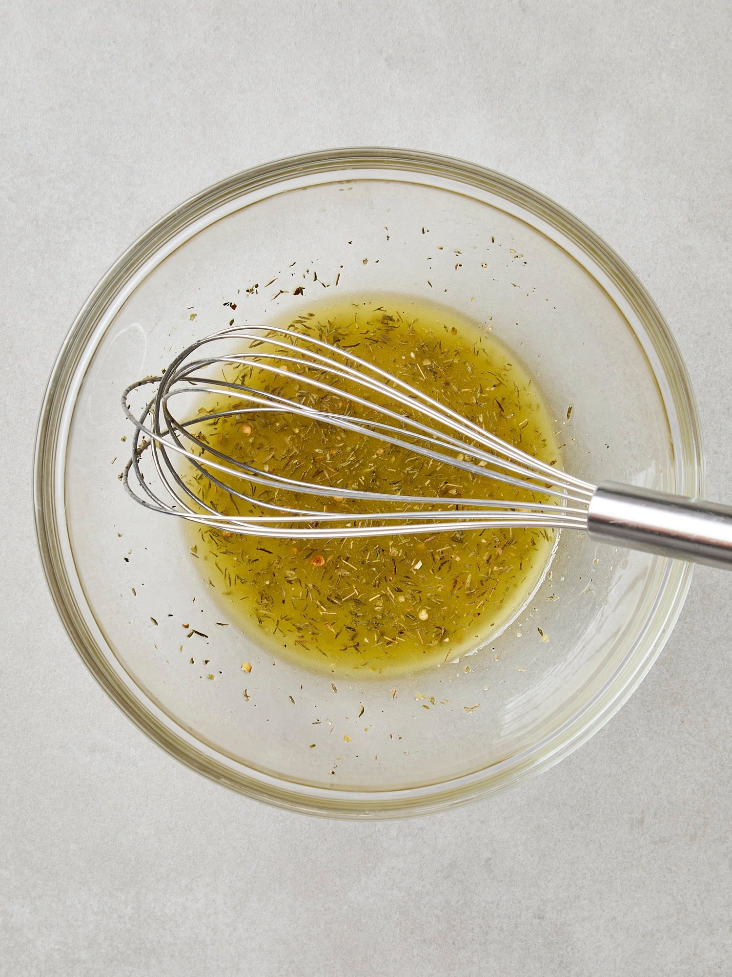 Glass bowl with dressing to be poured on top of greens.