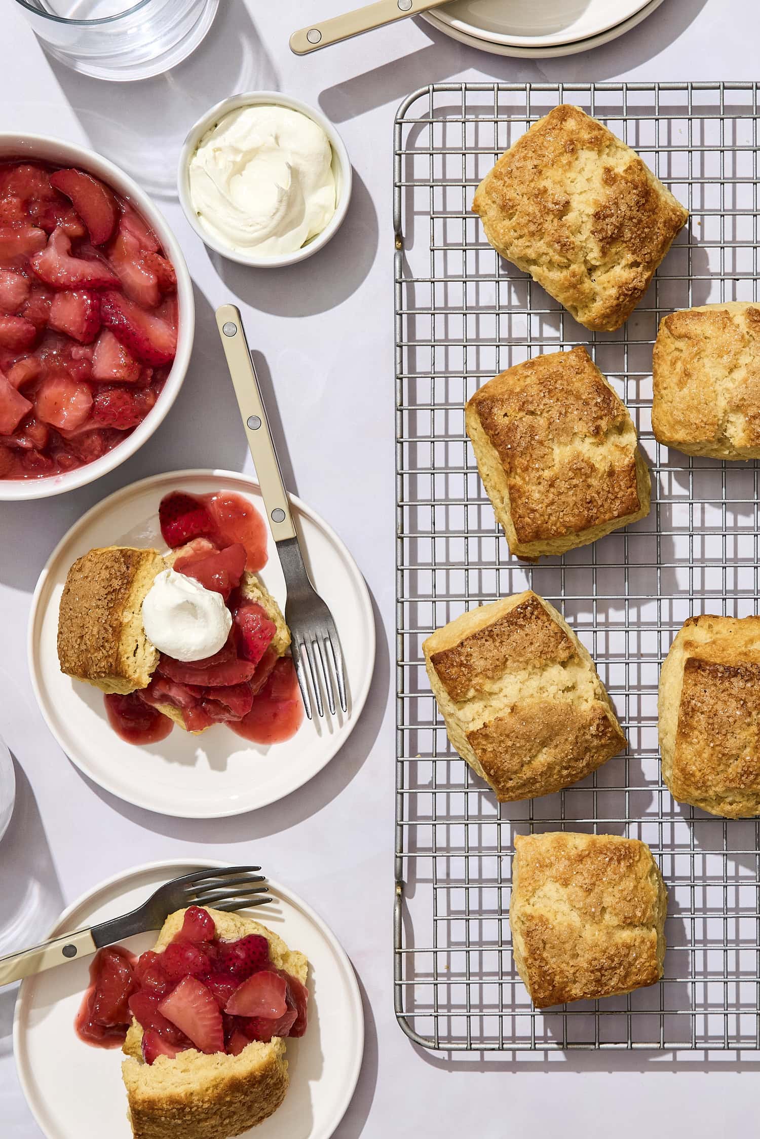 Plates with strawberry rhubarb shortcakes with biscuits on a cooling rack.