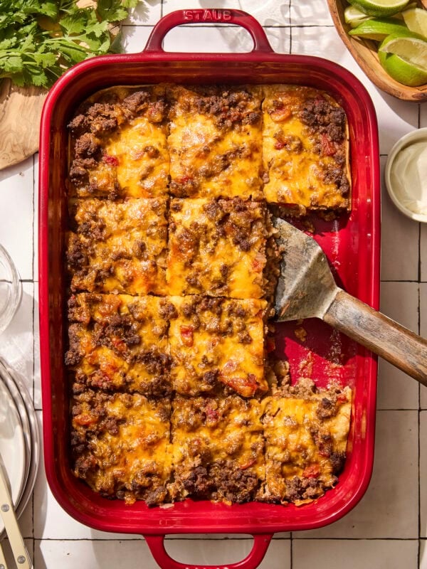 Baked taco casserole in red pan with slices cut.