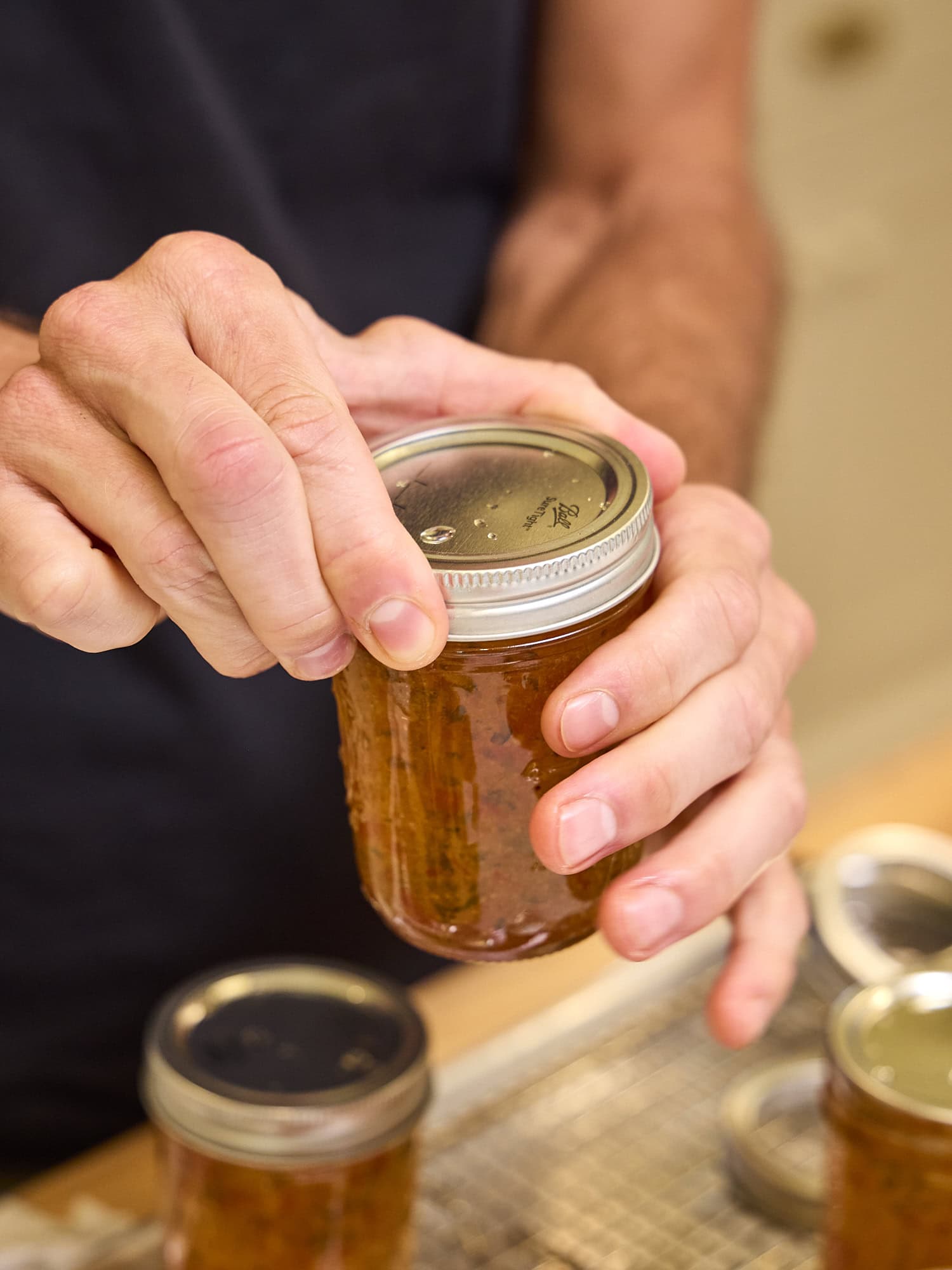 Tightening lid and ring on a jam jar for canning.