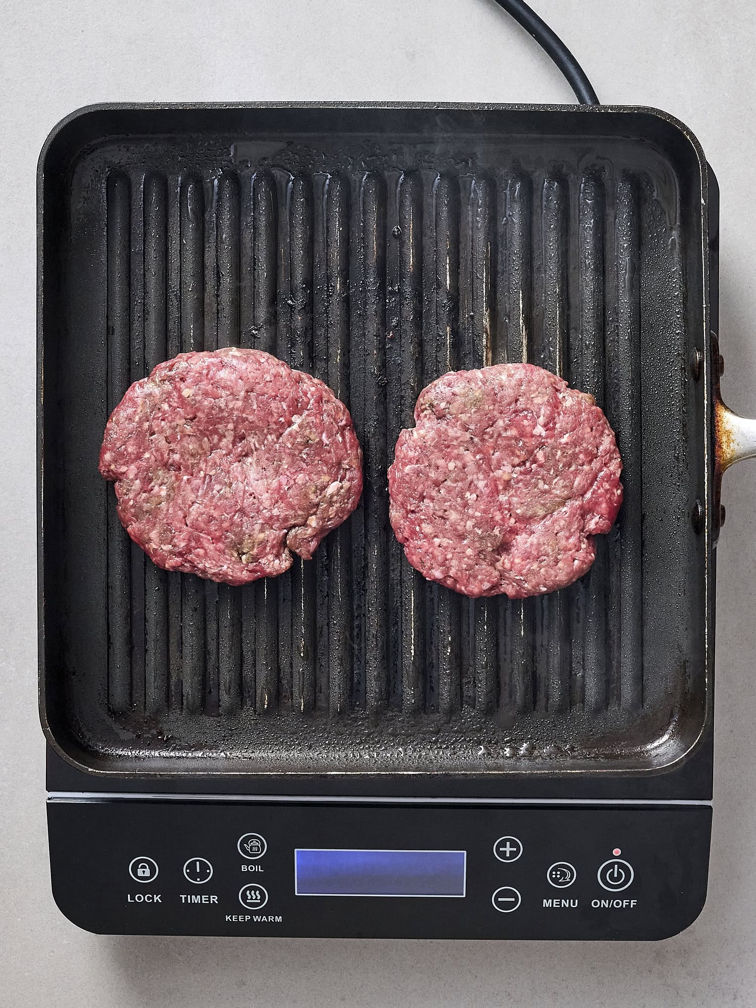 Uncooked burger patties on grill pan.