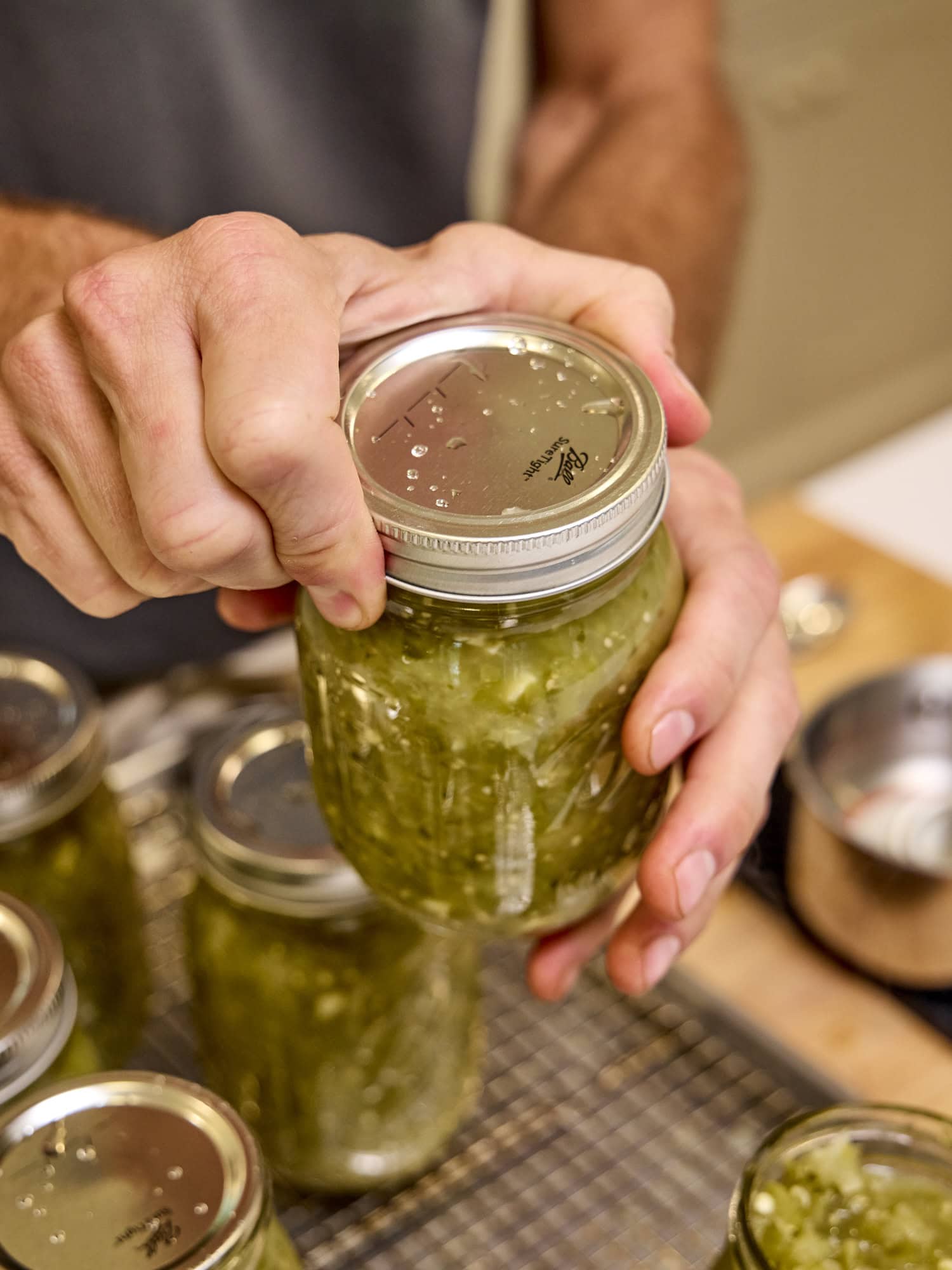 Adding the lid and ring to a jar filled with tomatillo salsa recipe.