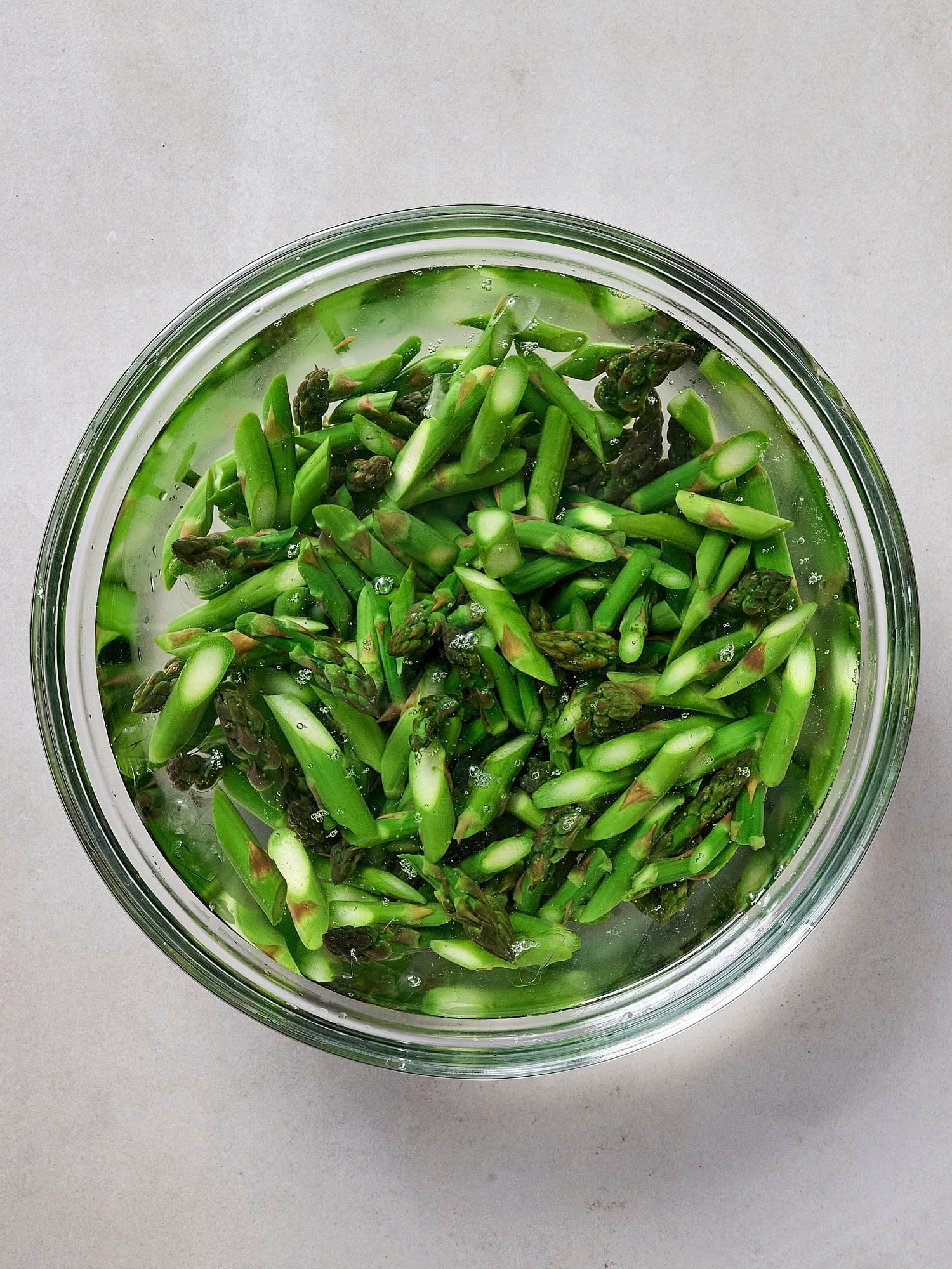 Chilling blanched asparagus in bowl.