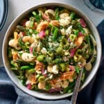 Bowl of asparagus salad topped with olives, tuna, and feta.