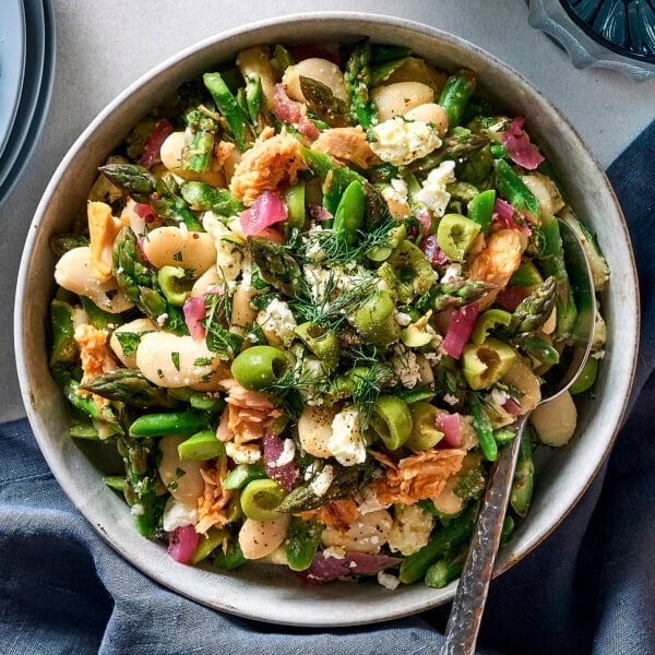 Bowl of asparagus salad topped with olives, tuna, and feta.