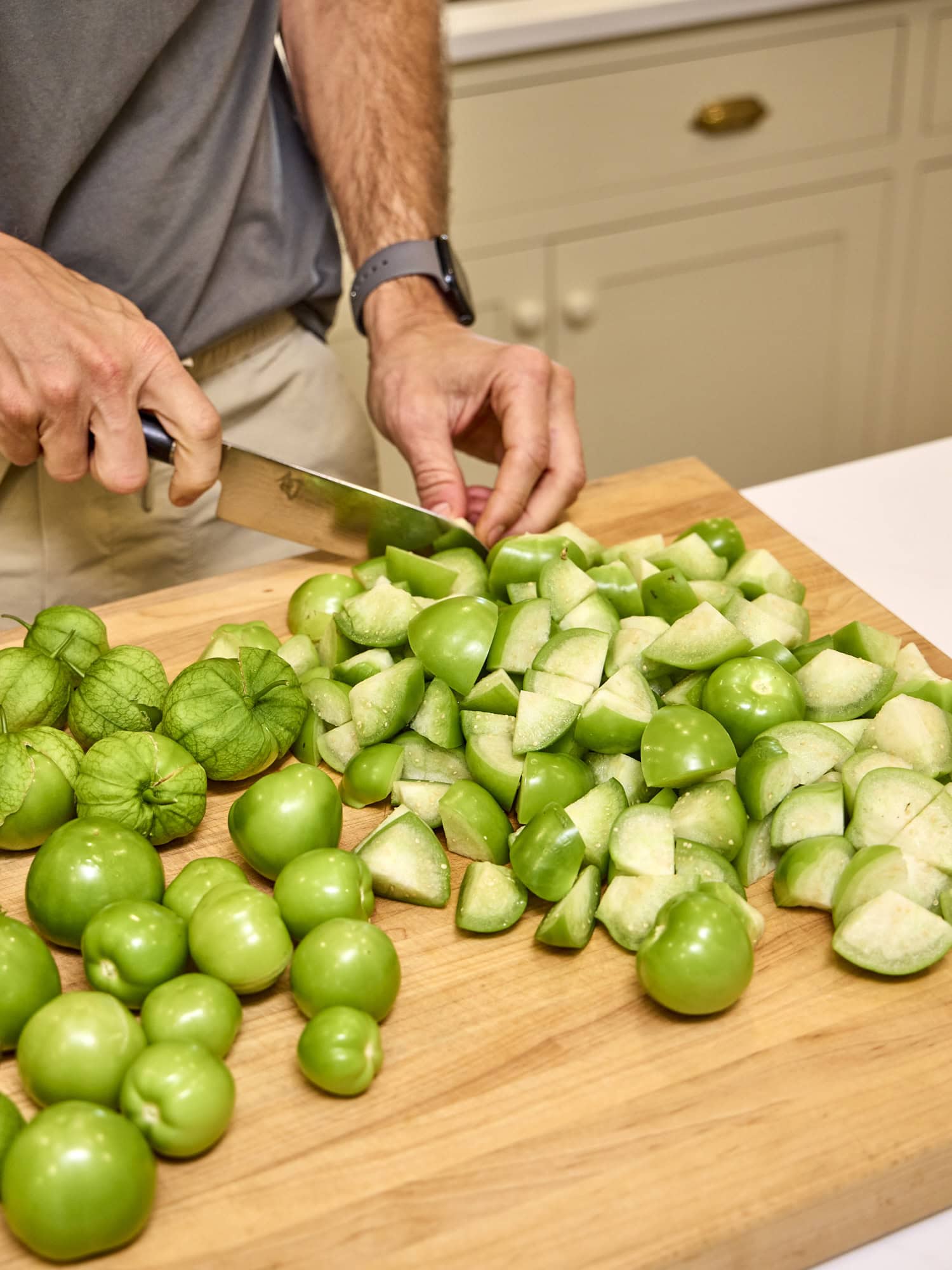 Cutting tomatillos into pieces for salsa recipe.