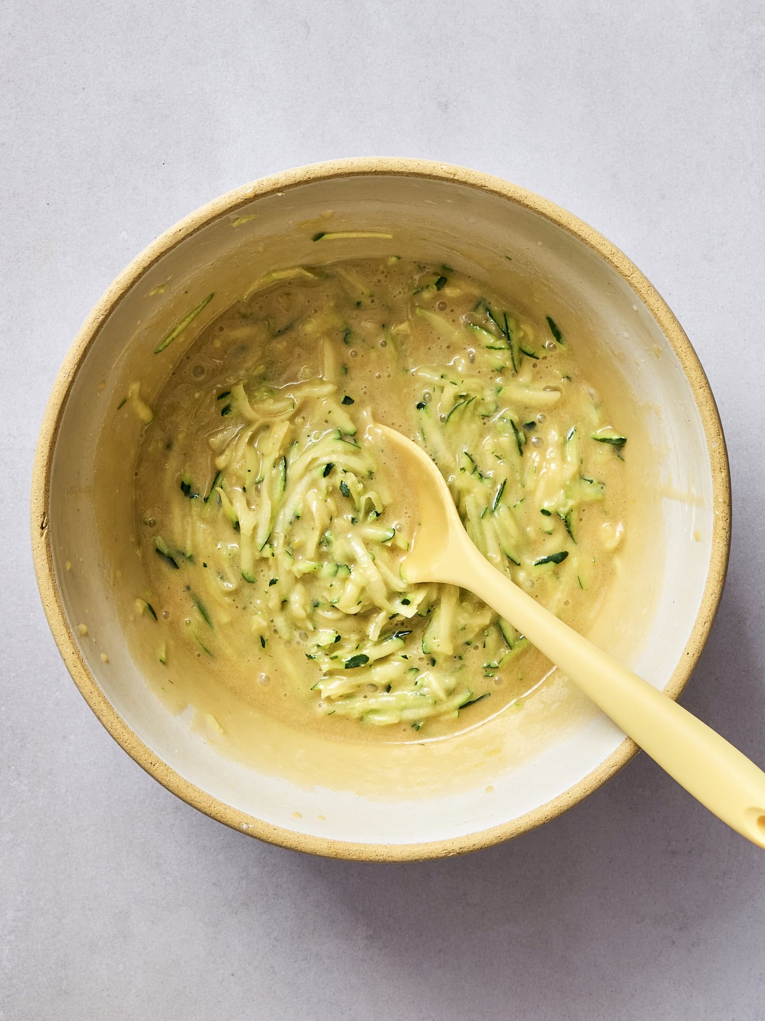 Zucchini added to bowl with wet ingredients for bread.