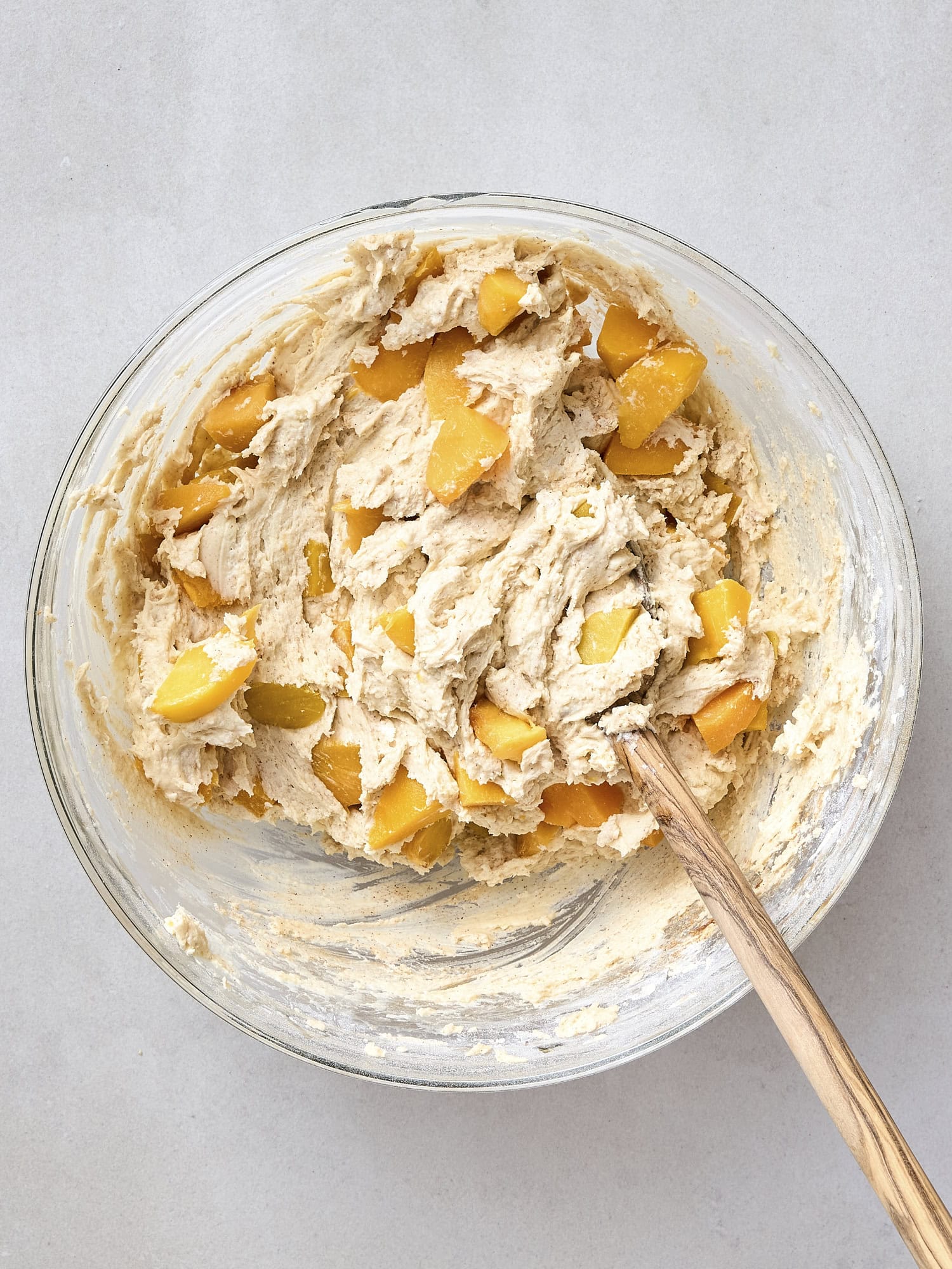 Bowl with diced peaches stirring together into batter.