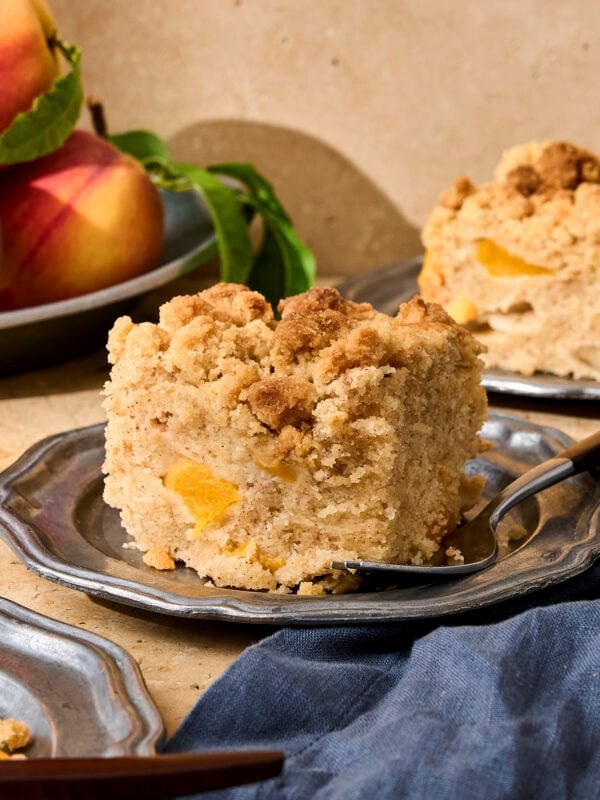 Slice of peach coffee cake on pewter plate.