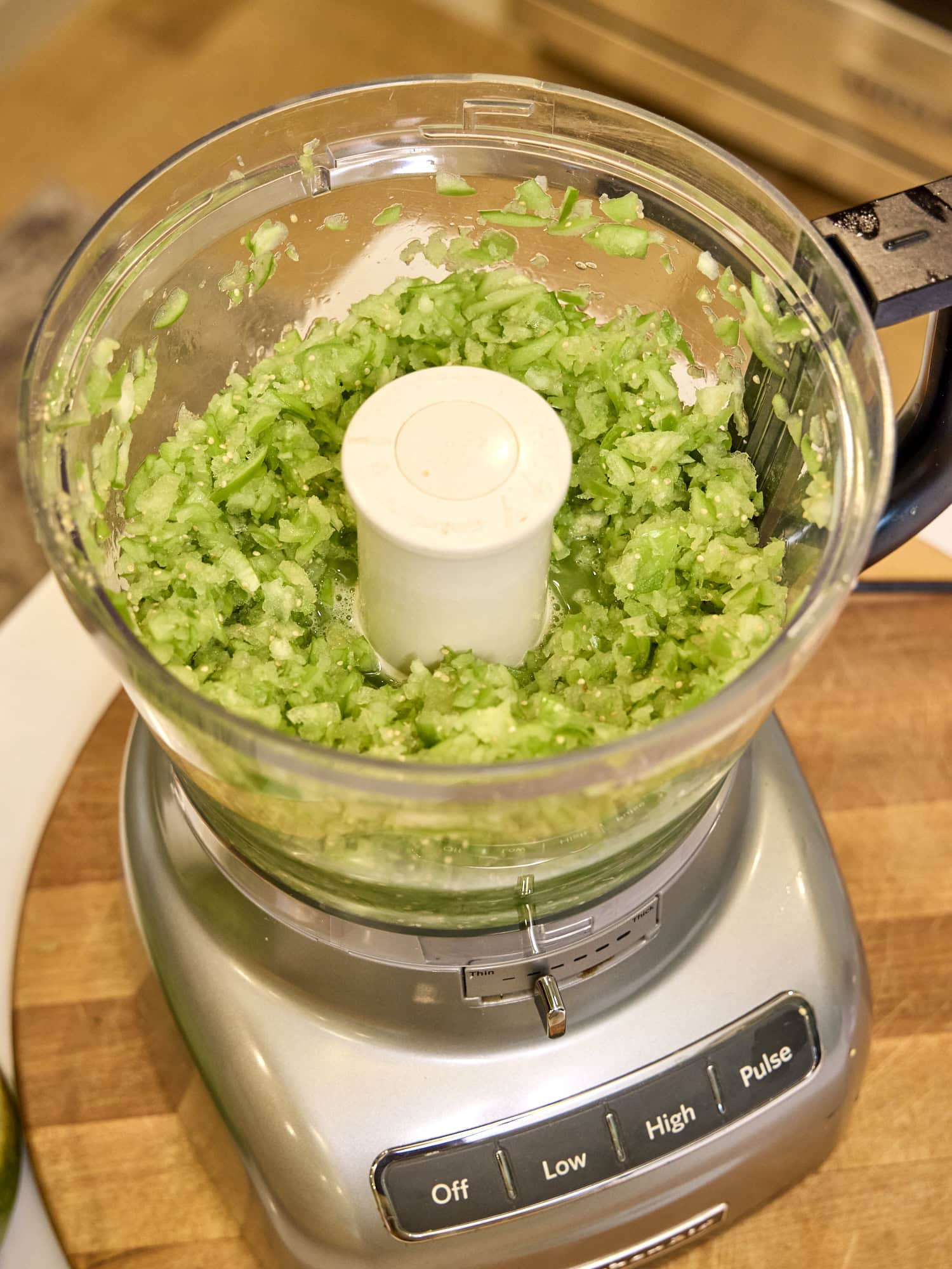 Chopped tomatillos in a food processor.