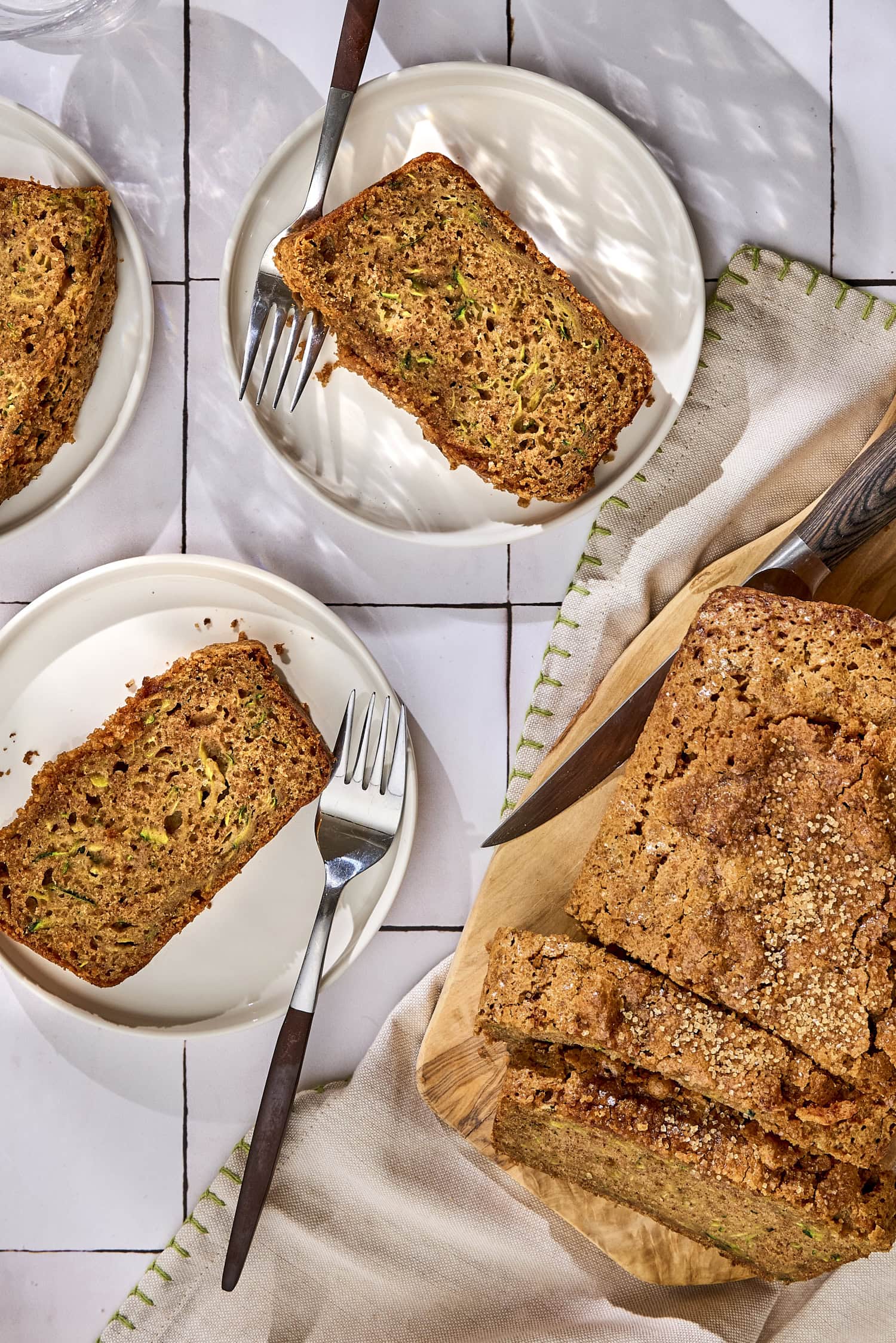 Two slices of zucchini bread on plates with loaf to the side.