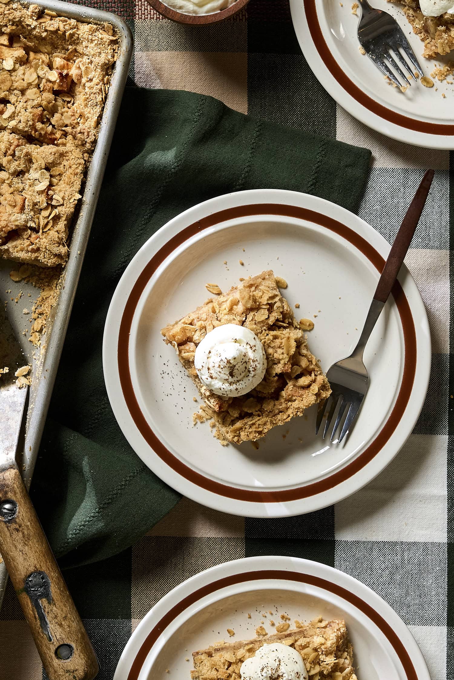 Apple pie bars on a plate with whipped cream on top.