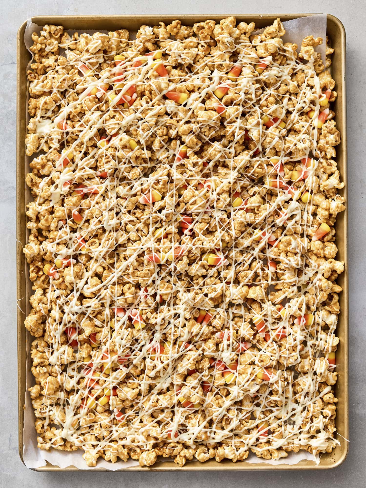 Peanut butter popcorn drizzled with white chocolate with candy corn pieces.