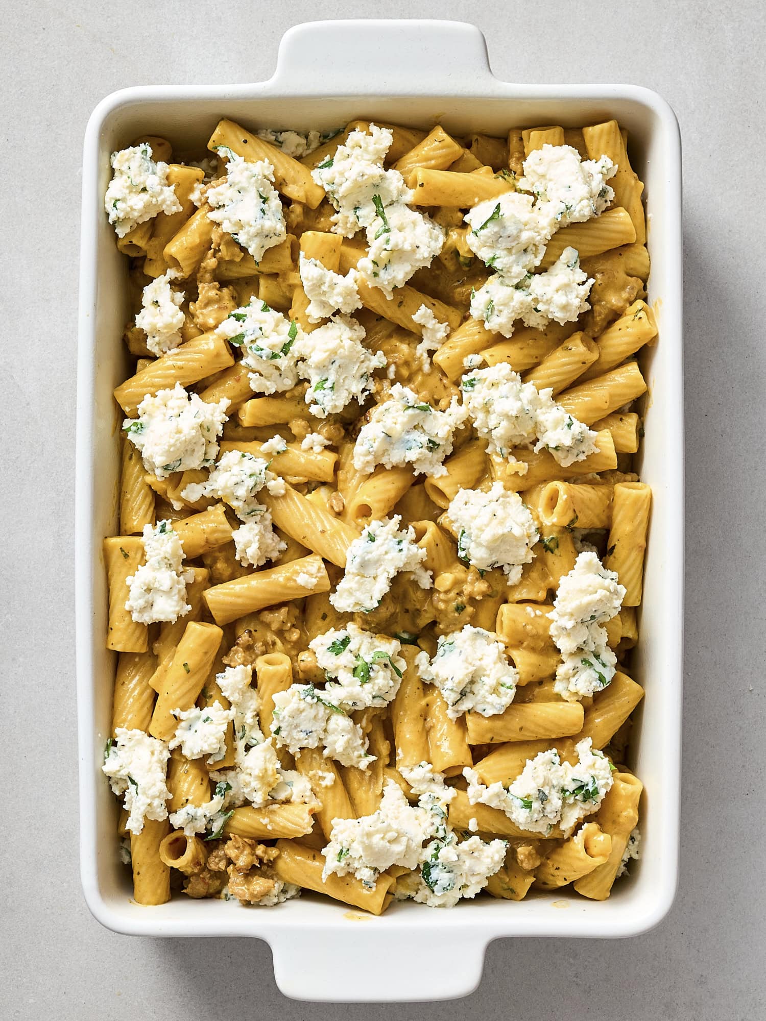 Layering dollops of ricotta mixture for pumpkin baked ziti.