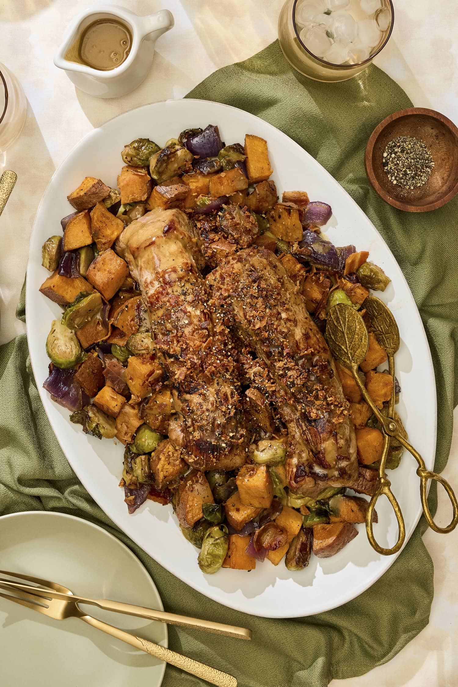 Platter with roasted pork tenderloin with vegetables underneath.