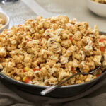 Bowl of peanut butter popcorn with candy corn and white chocolate.