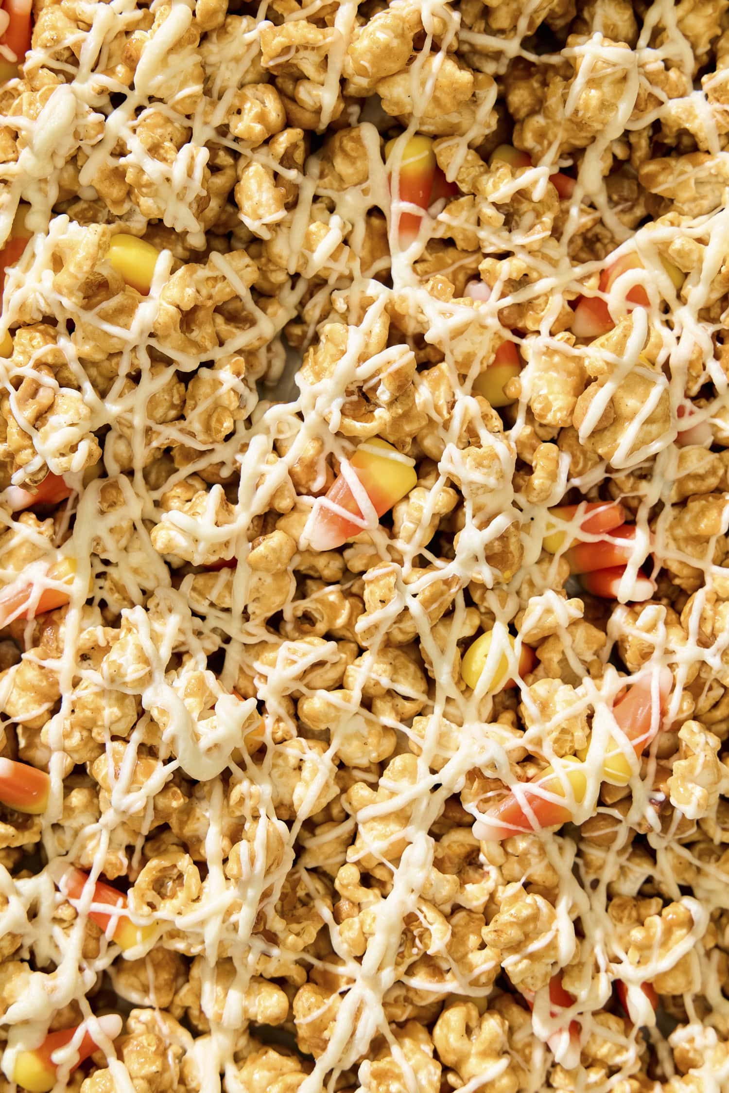Close up of drizzled popcorn with white chocolate and candy corn pieces.