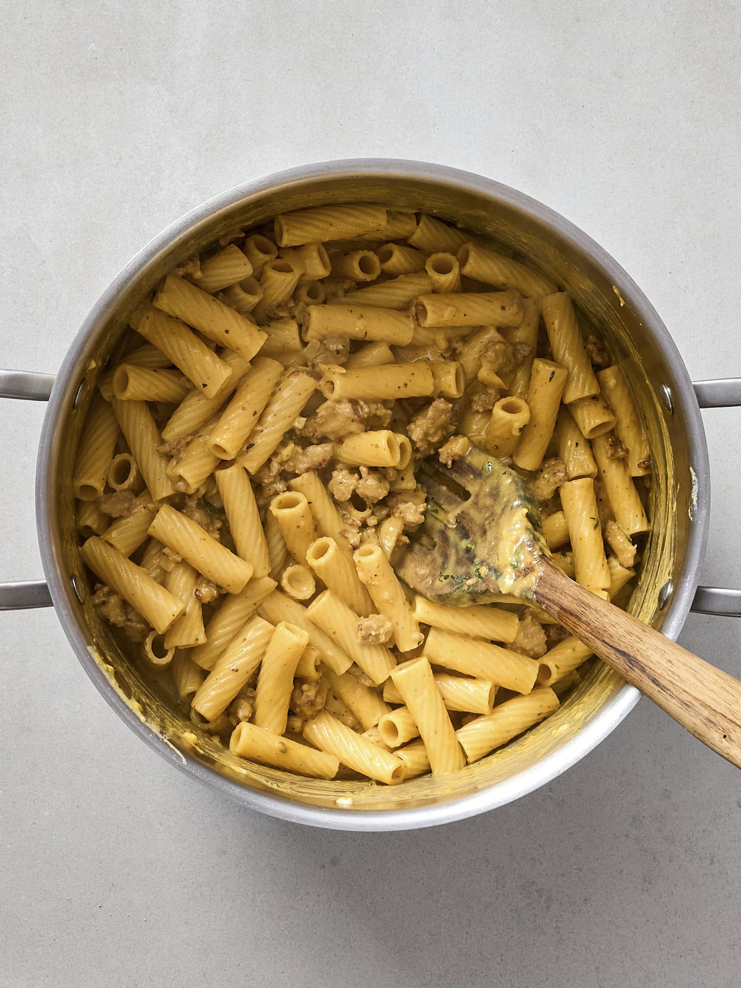 Stirring pasta with pumpkin sausage sauce.