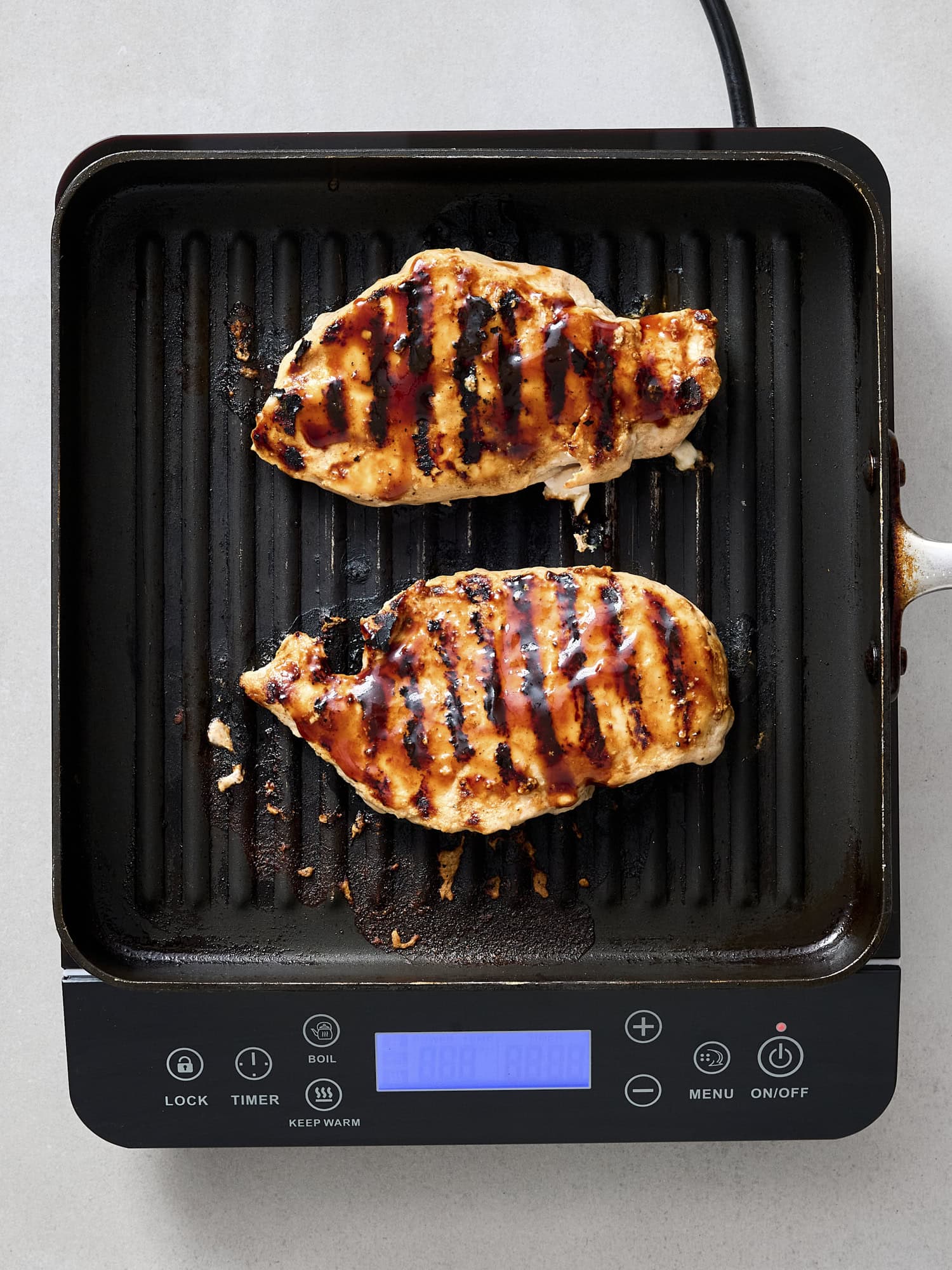 Grilled chicken breast on grill with BBQ sauce.