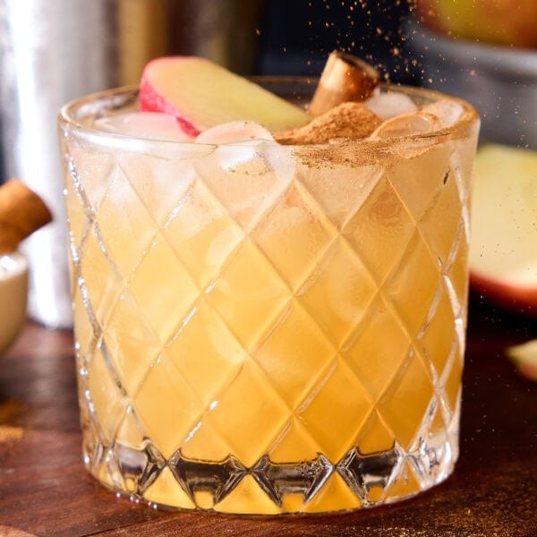 Cinnamon sprinkles fall on top of an apple cider margarita.