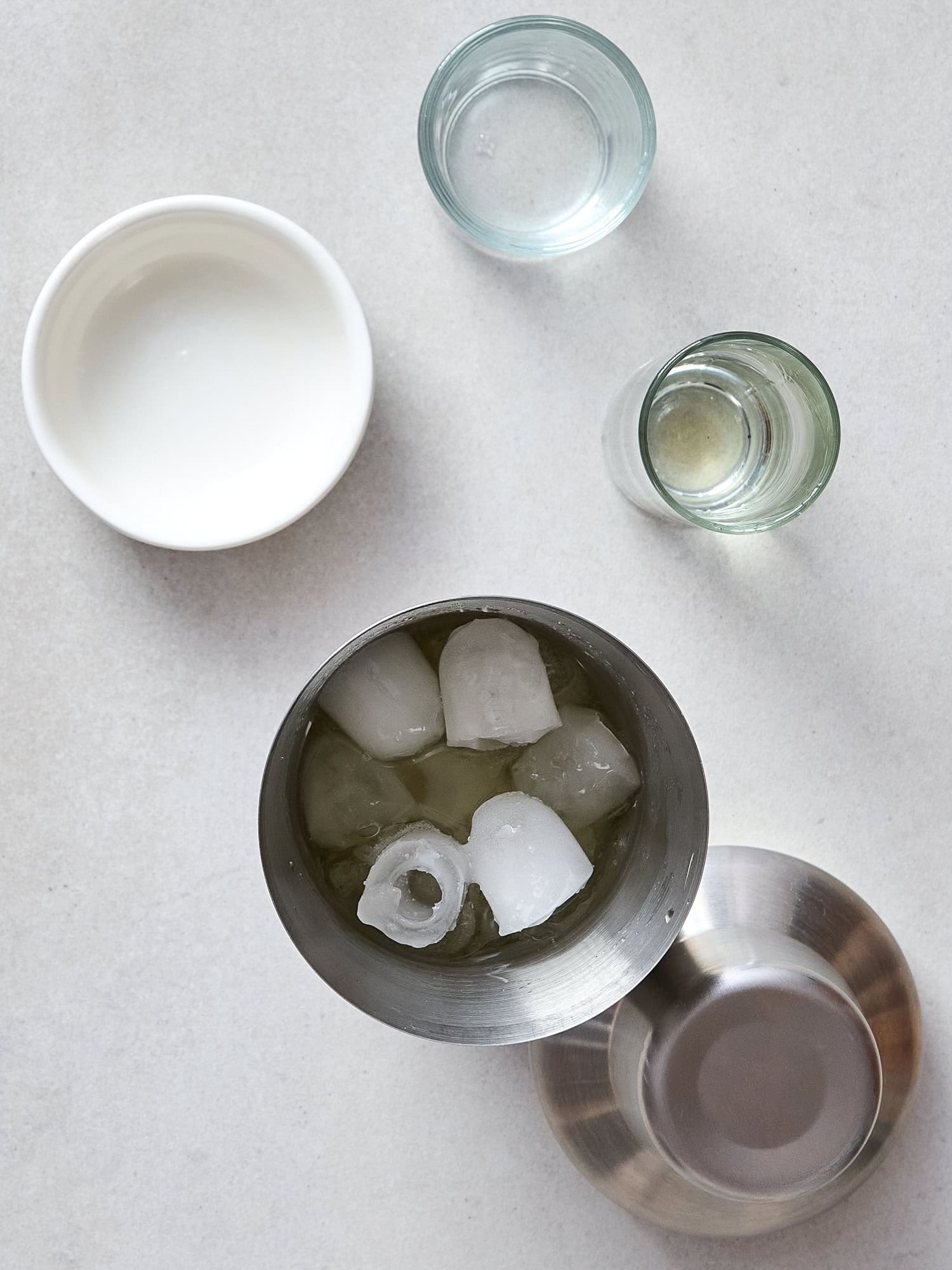 A cocktail shaker filled with ingredients for an apple cider margarita sits on a counter.