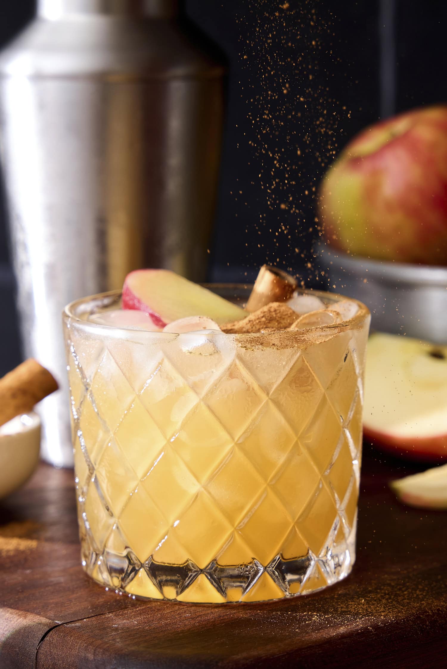 Cinnamon being sprinkled over the top an apple cider margarita.