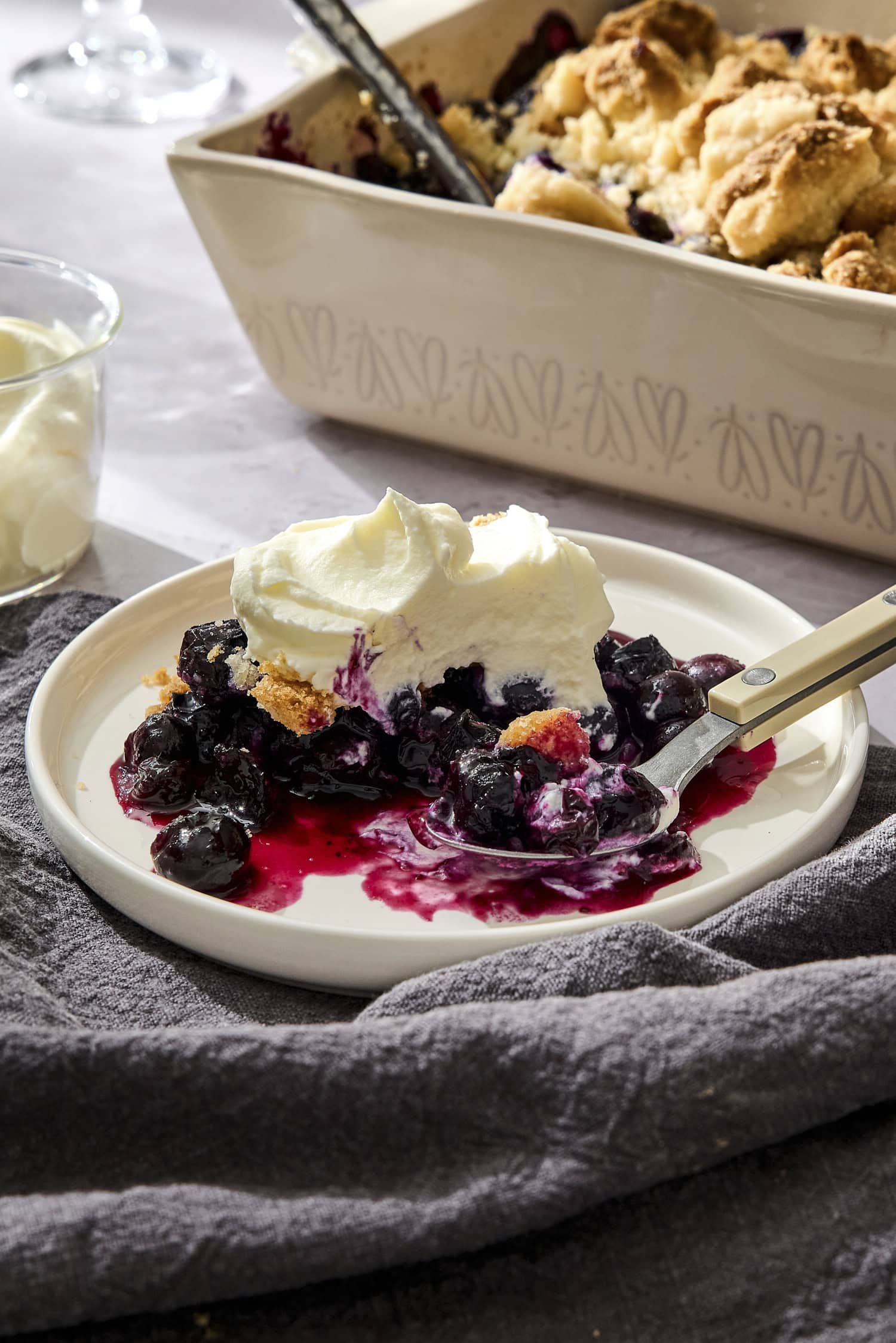 A serving of blueberry crumble topped with whipped cream.