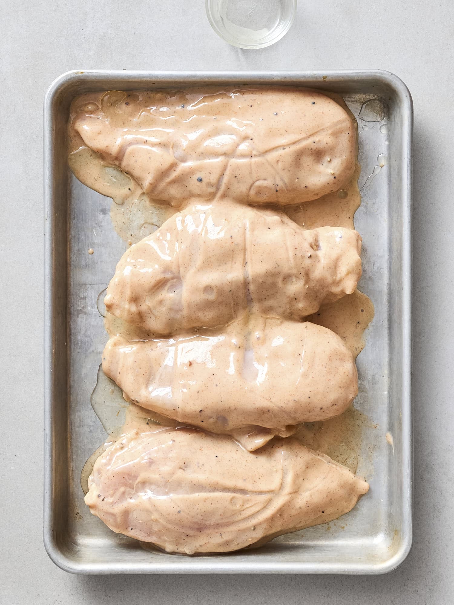 Letting marinade drip off chicken before grilling.