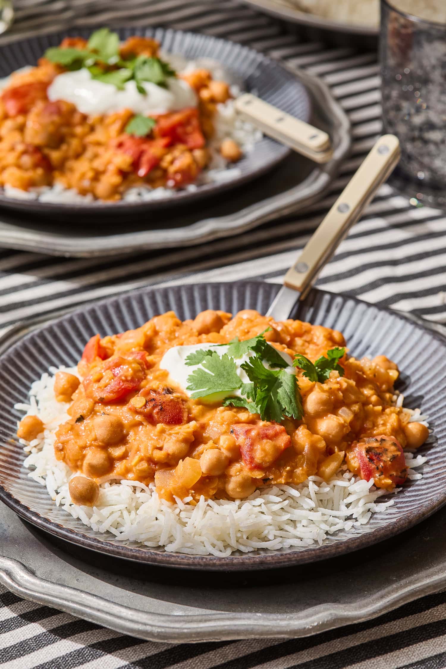 Lentil and chickpea curry recipe sits on top of rice with cilantro and Greek yogurt.
