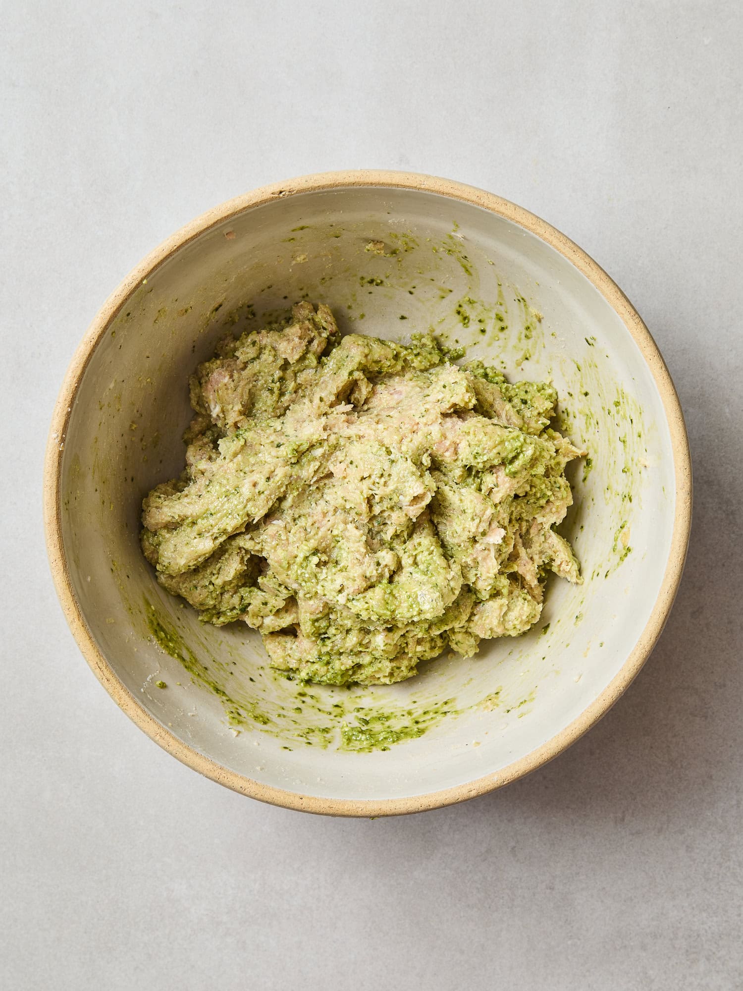 A pesto and ground chicken meatball mixture in a bowl.
