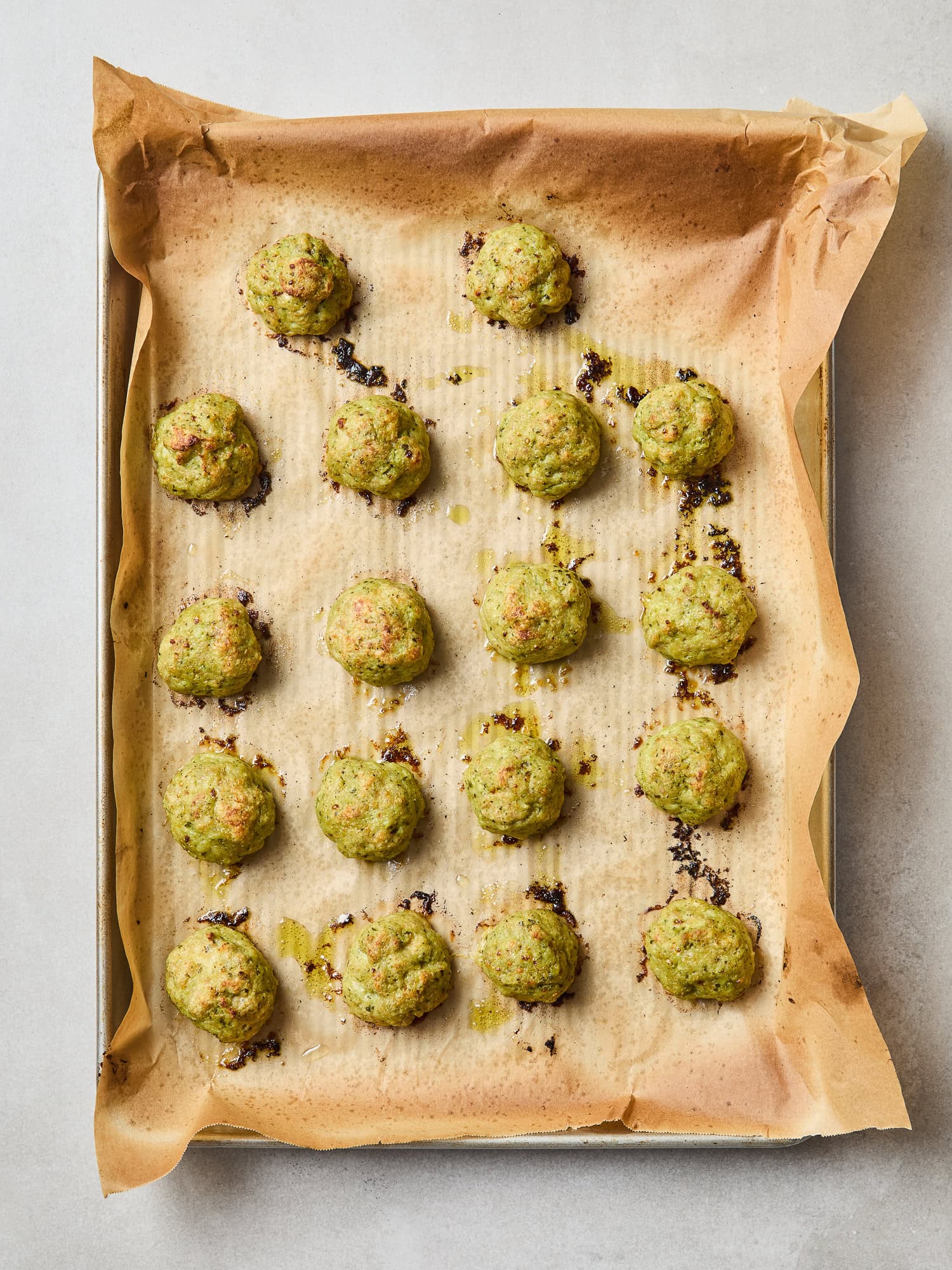 Roasted pesto chicken meatballs sit on a baking sheet.