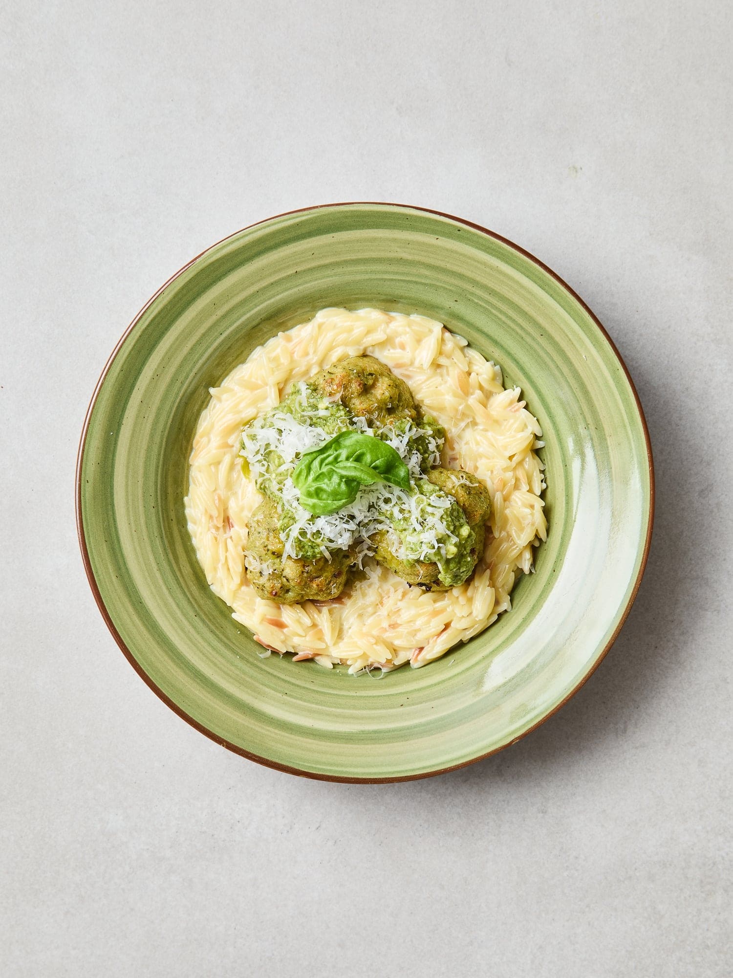 Chicken meatballs sitting on top of creamy orzo in a bowl.