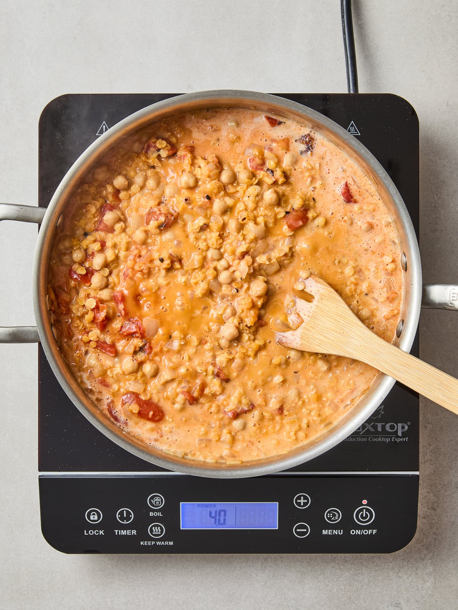 Lentil and chickpea curry simmer with coconut milk in a skillet.